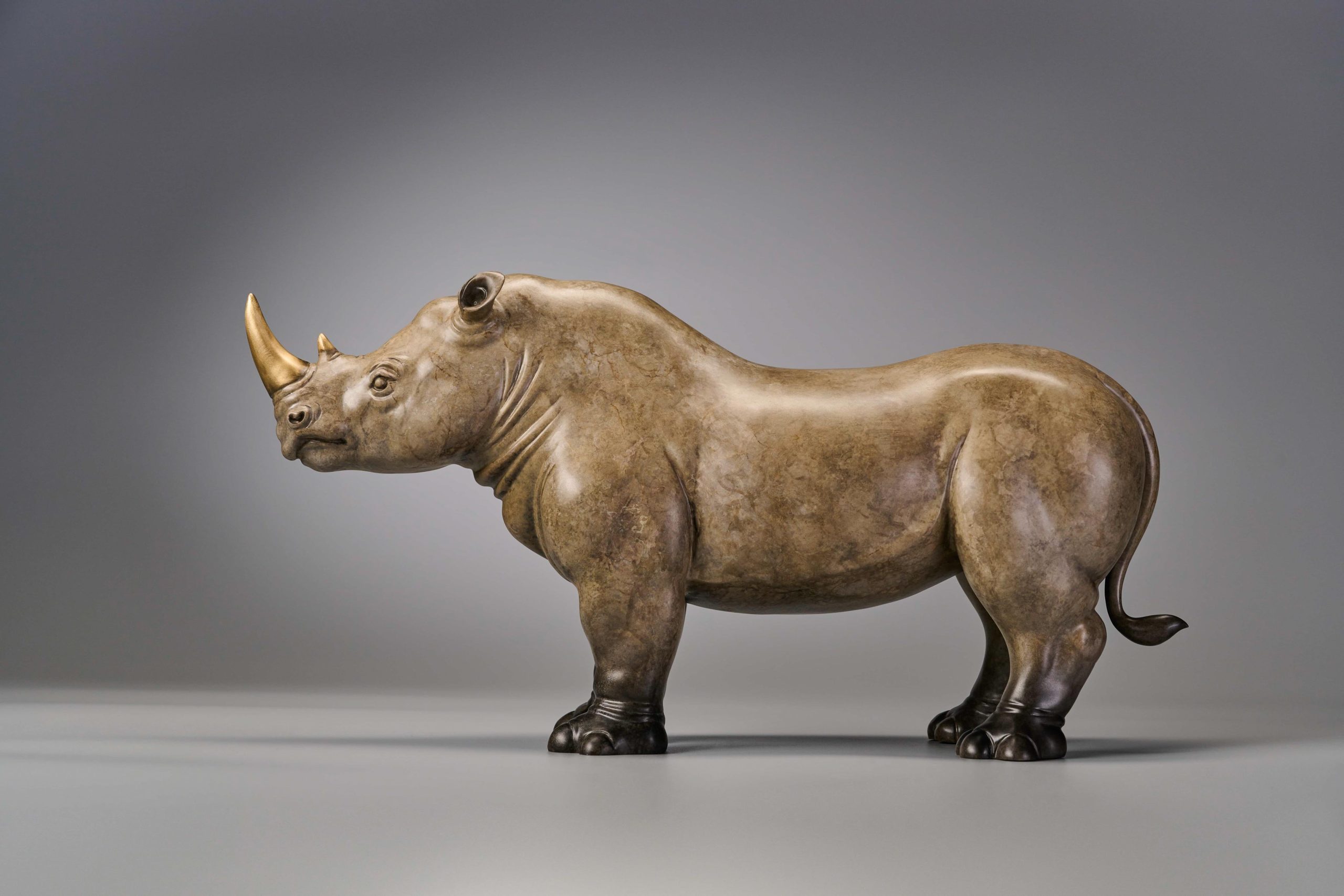 Pair of stylized rhinos in amber and grey — grey rhino side view.