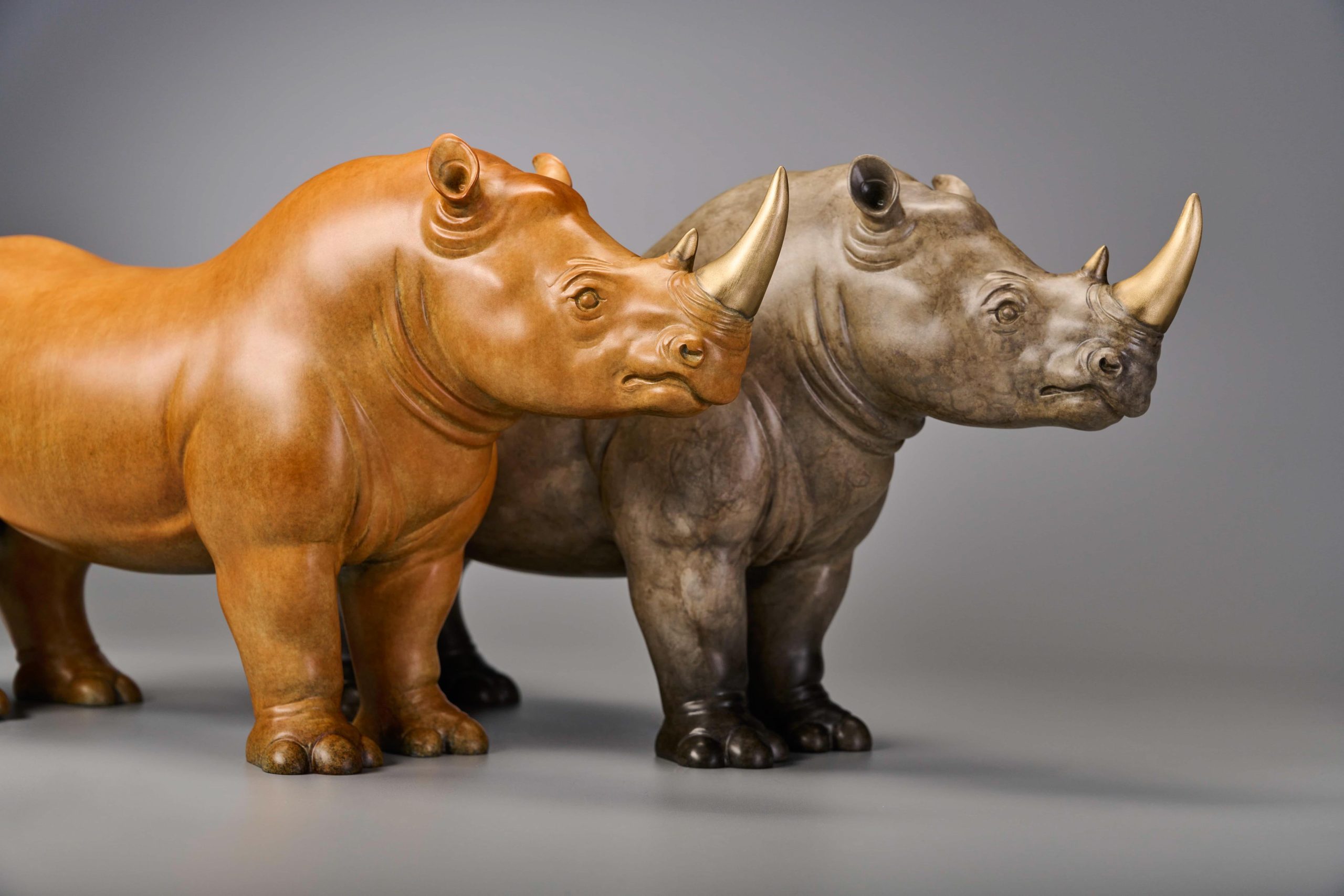 Pair of stylized rhinos in amber and grey — pair side by side.