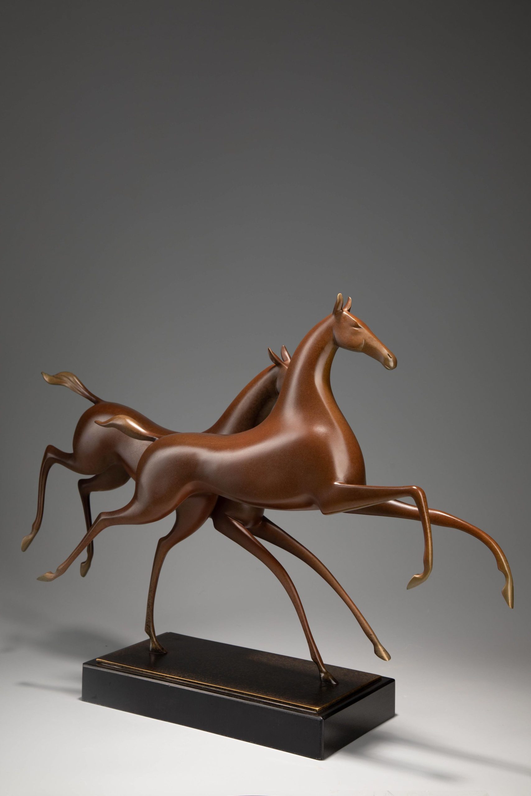 Running horse pair in warm sienna — rear three-quarter.