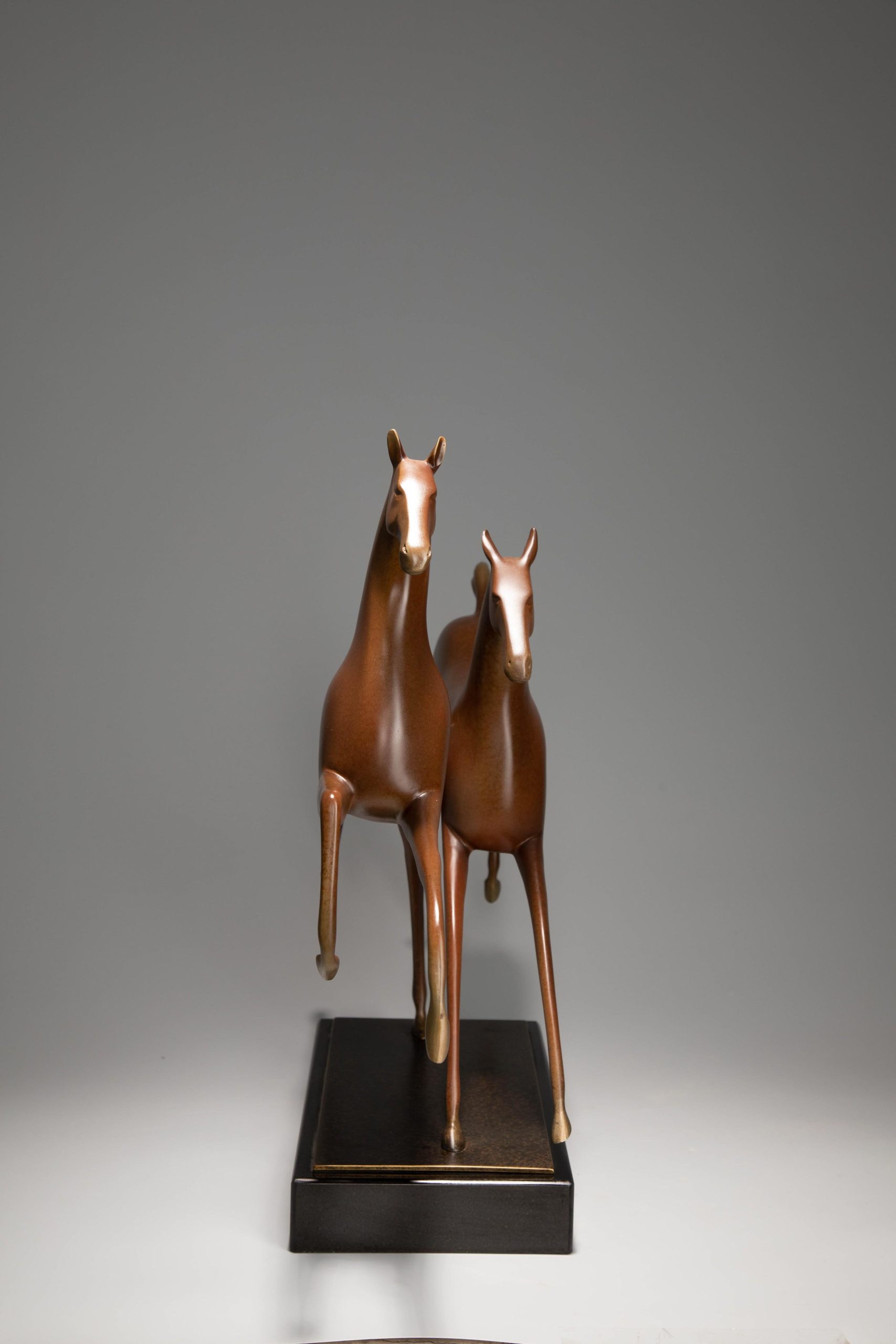 Running horse pair in warm sienna — front view.