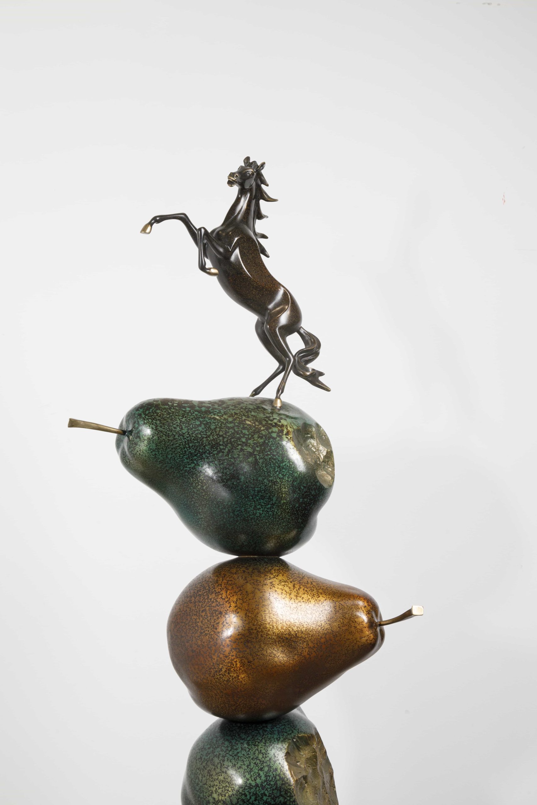 Dark bronze rearing horse atop stacked pears — upper section close-up.