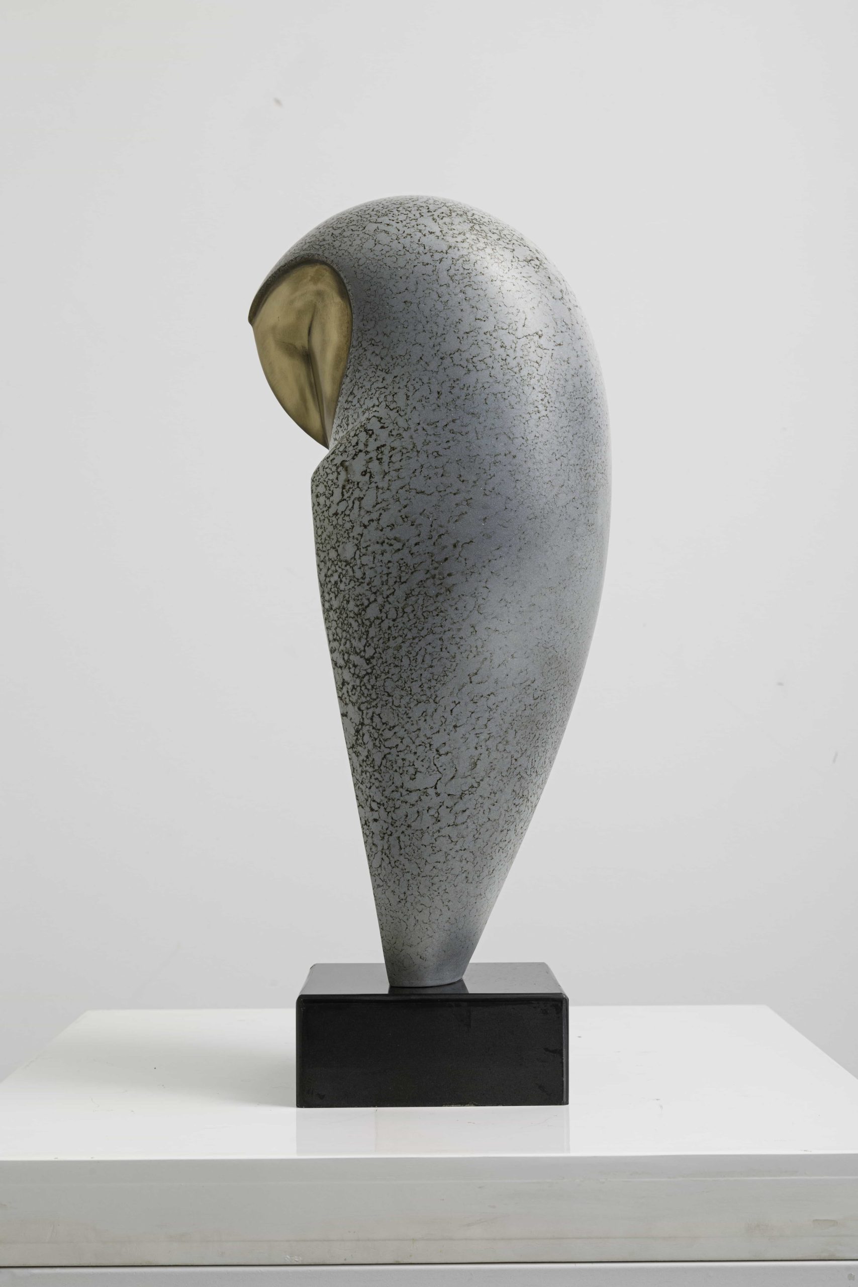 Speckled owl with brass heart-shaped face — side view.