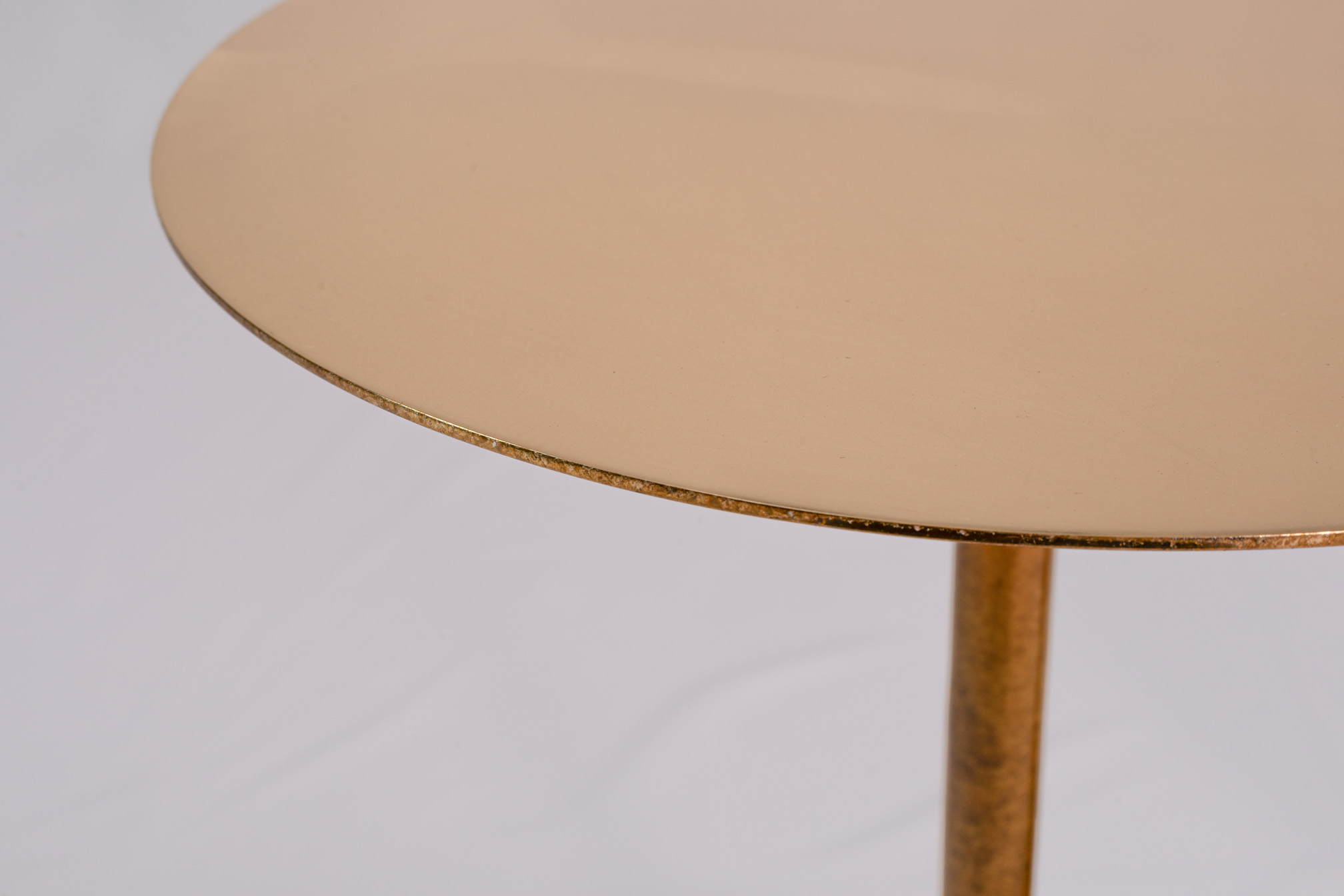 Edge of the round bronze tabletop with the slender support column