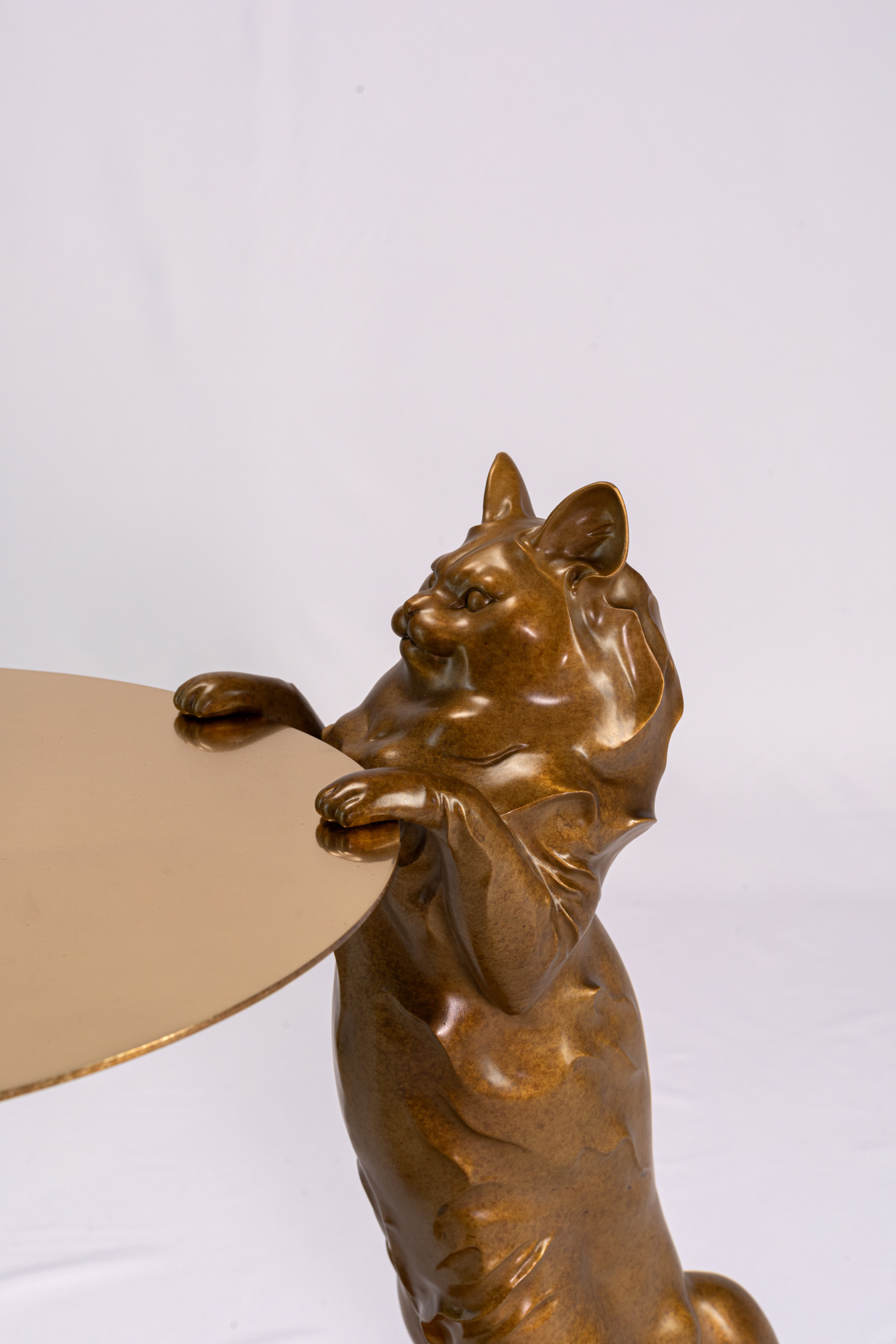 Detail of the bronze cat's front paws resting on the round table edge
