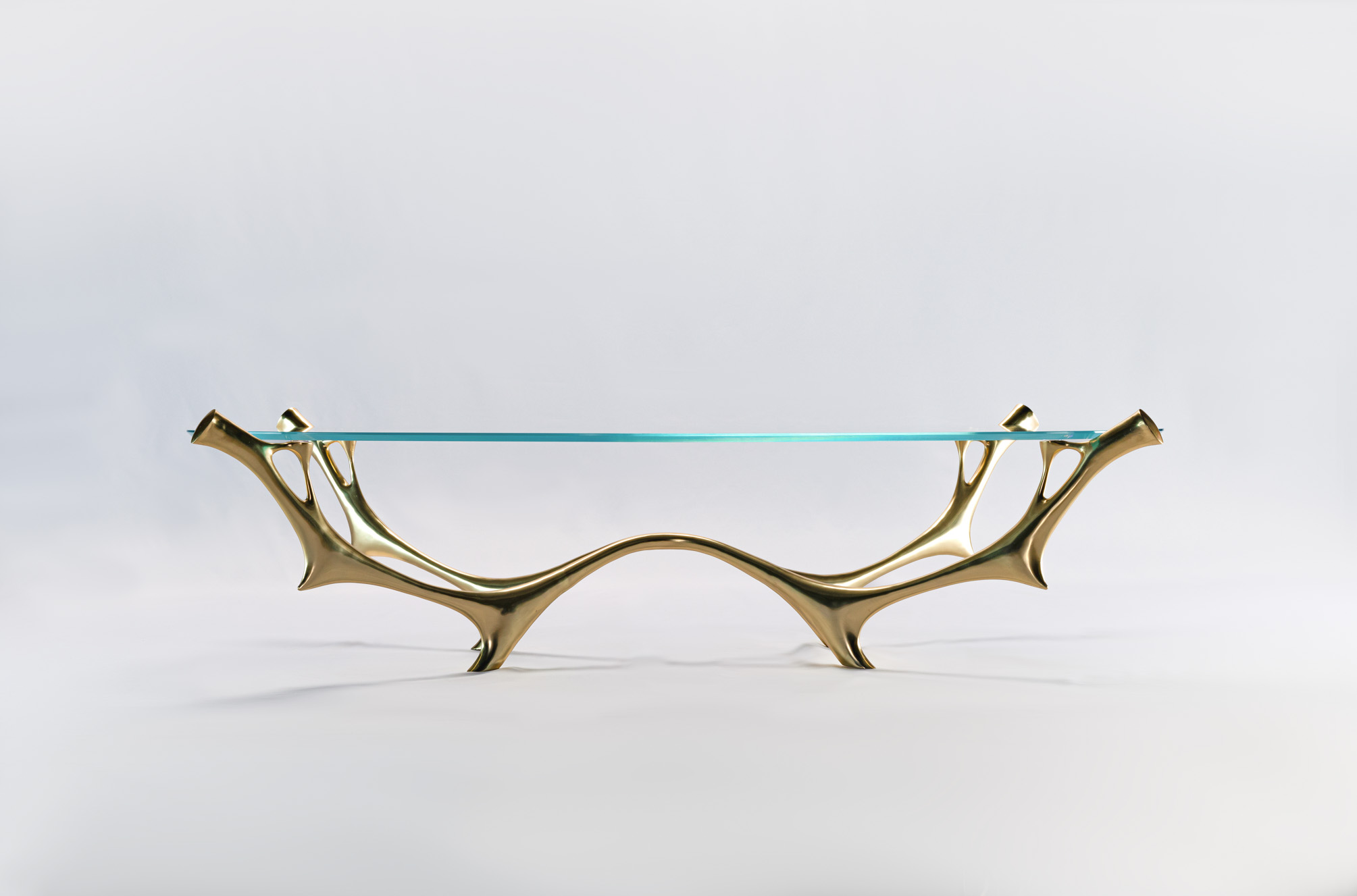 Abstract water-and-branch form bronze coffee table with oval glass top, three-quarter view