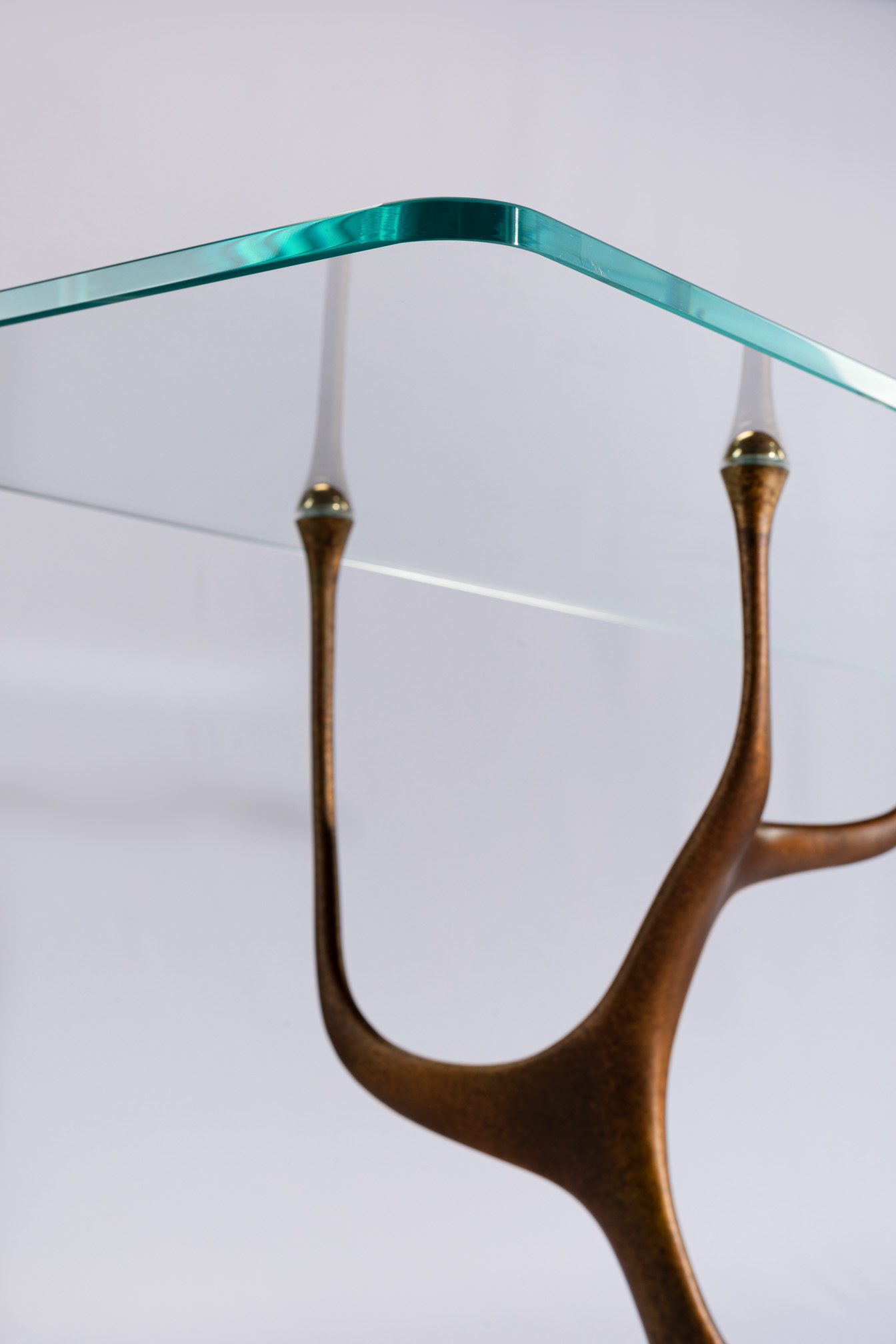 Detail of the clear glass top edge meeting the bronze antler tips of the console table