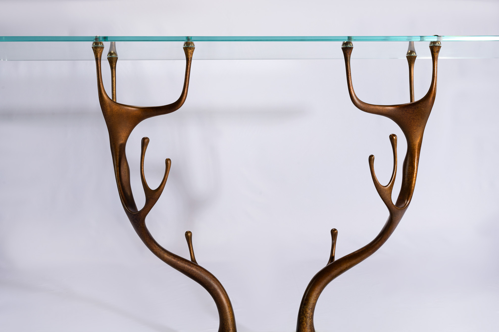 Front view of the deer antler bronze legs and bevel-cut clear glass top of the console table