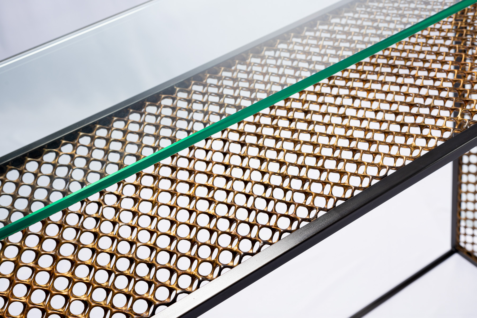 Detail of the glass edge and bronze mesh grid of the console table