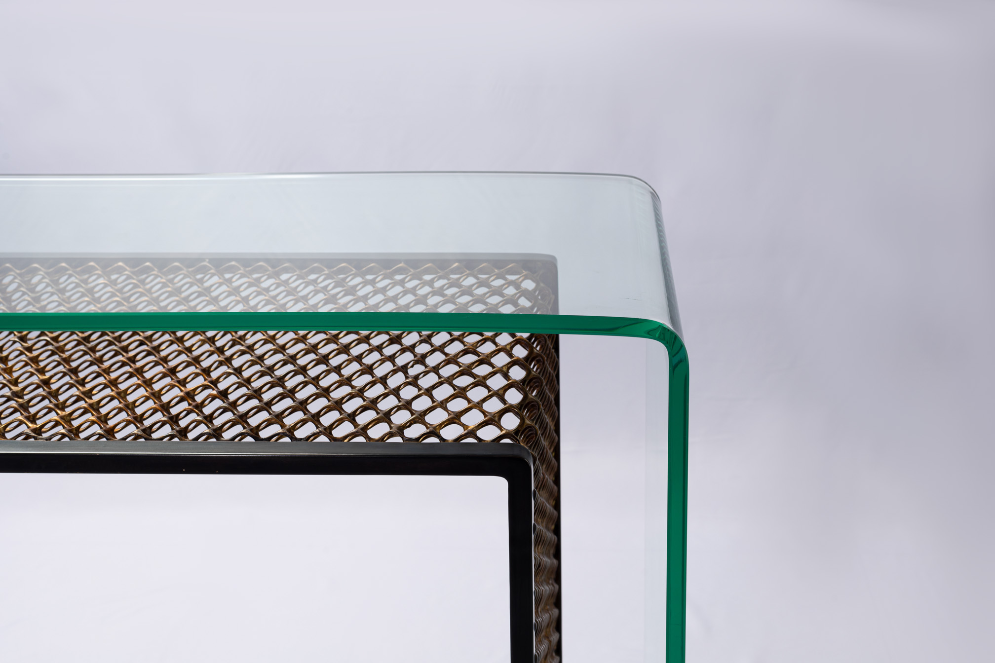 Detail of the curved glass corner of the bronze mesh console table