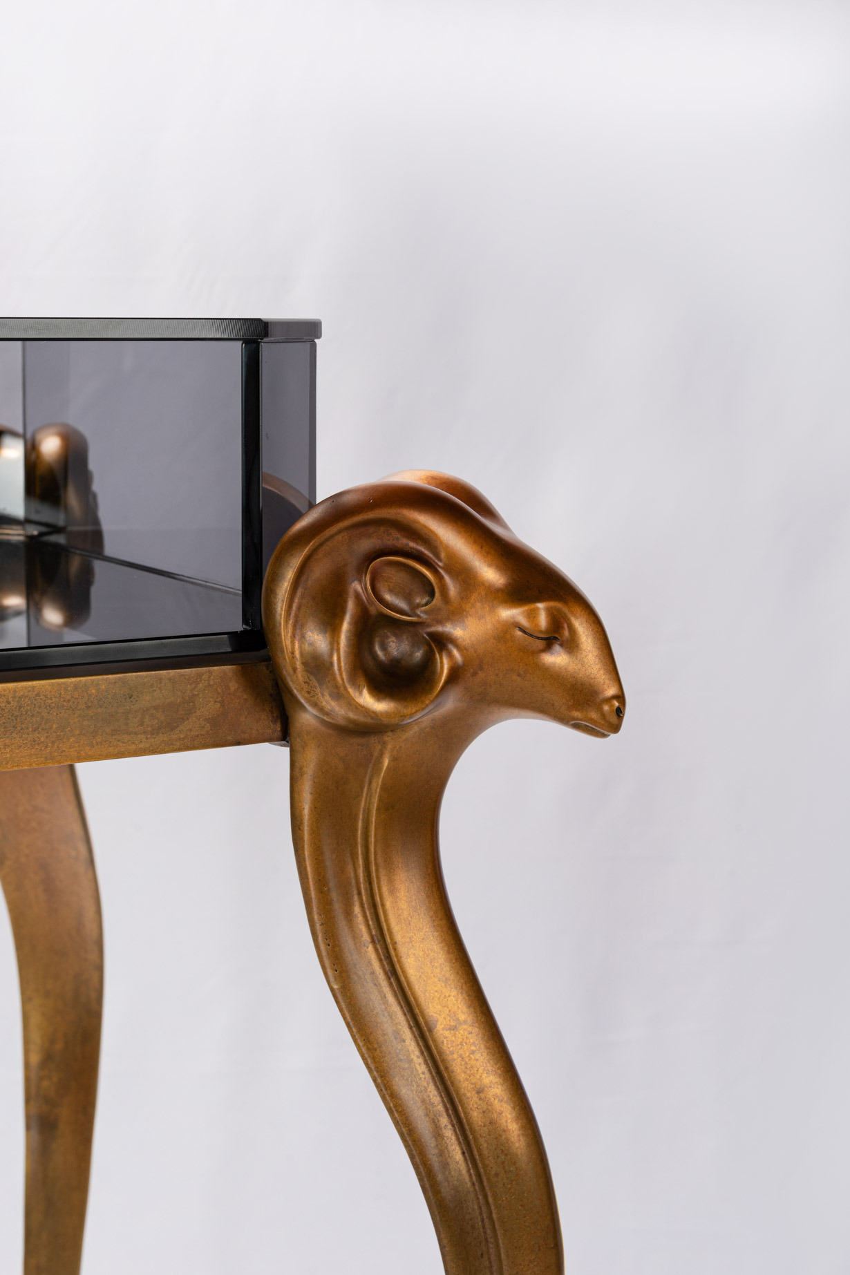 Close-up of the antelope head bronze capital supporting the smoked glass top