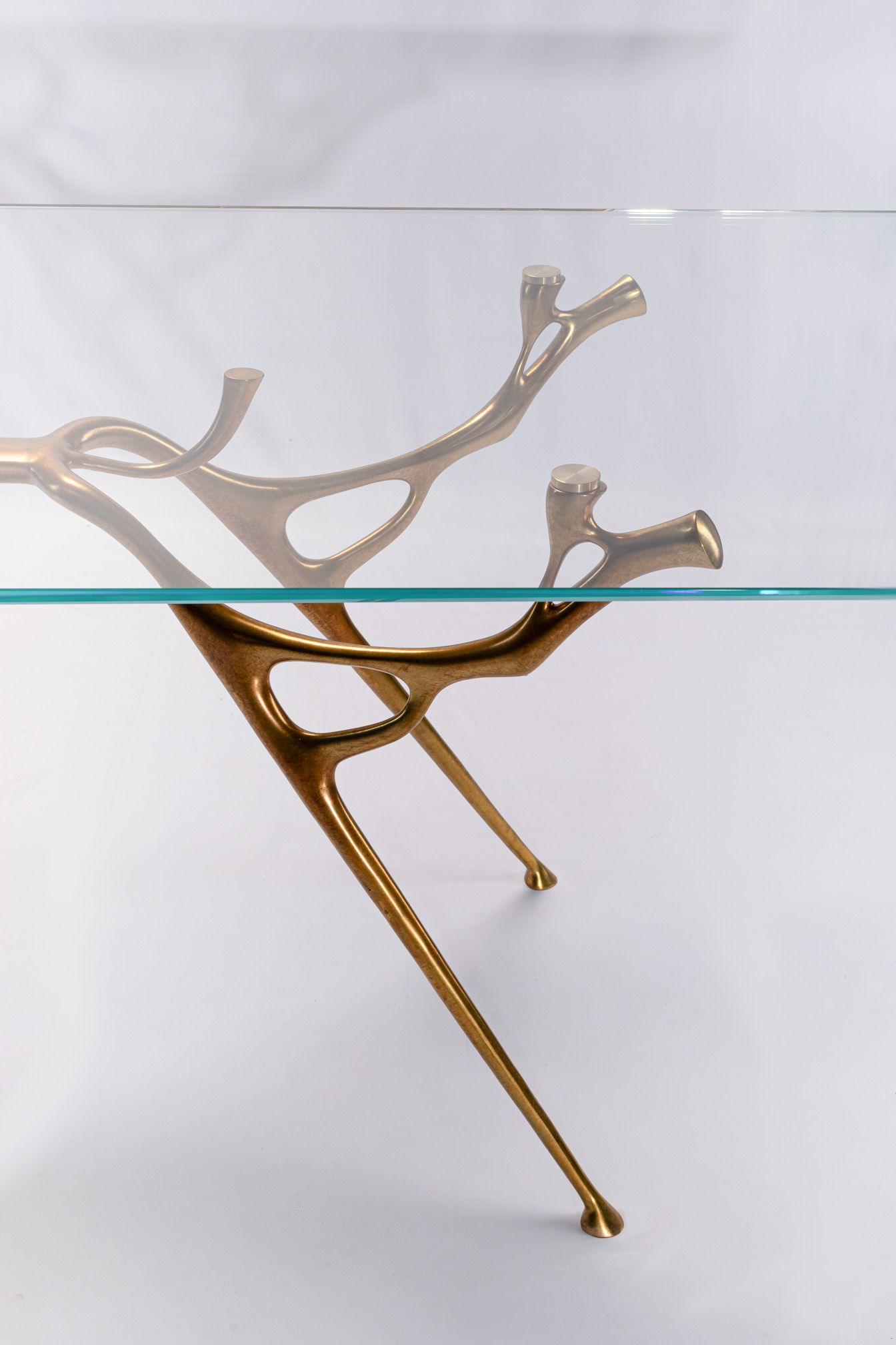 Three-quarter view of the abstract water-and-branch bronze dining table