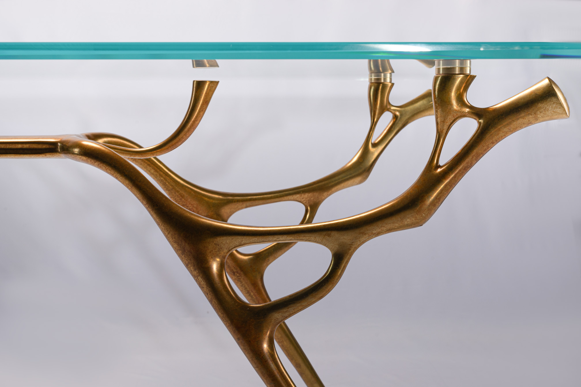 Detail of the water-and-branch bronze legs spreading under the glass top