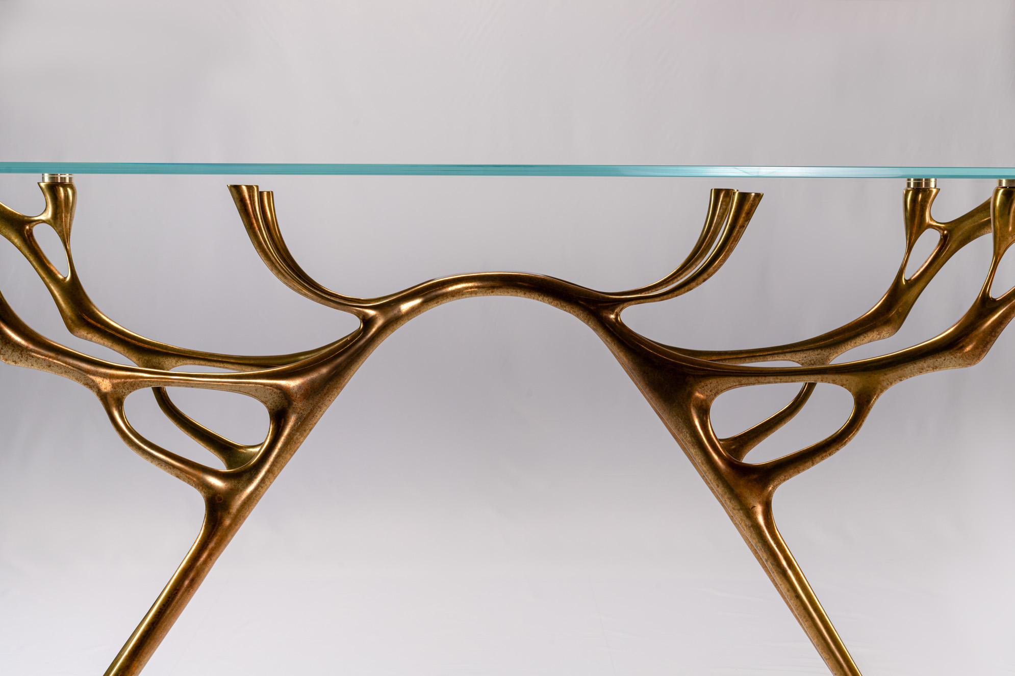 Detail of the water-and-branch bronze form spreading under the glass top