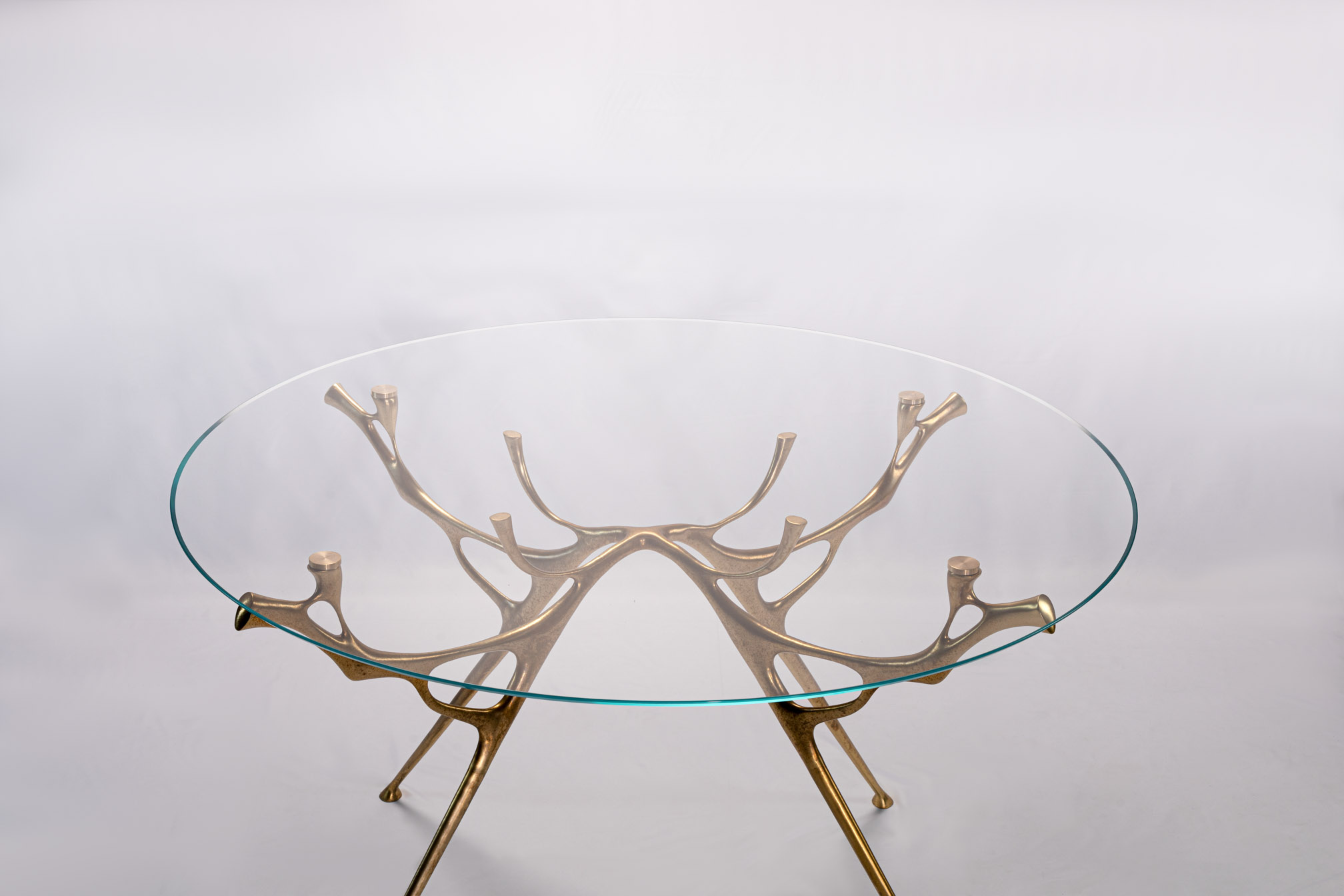 Front view of the round bronze dining table with glass top