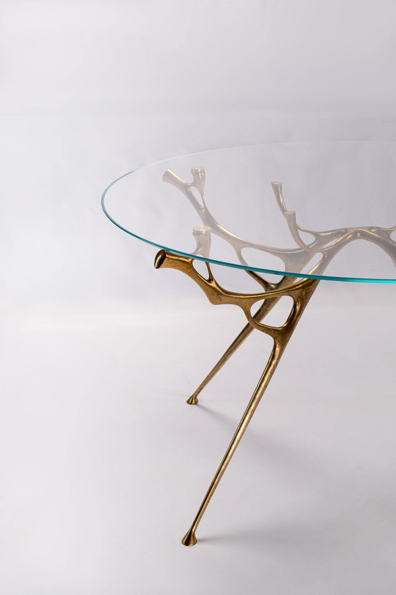 Round glass-top bronze dining table, side view