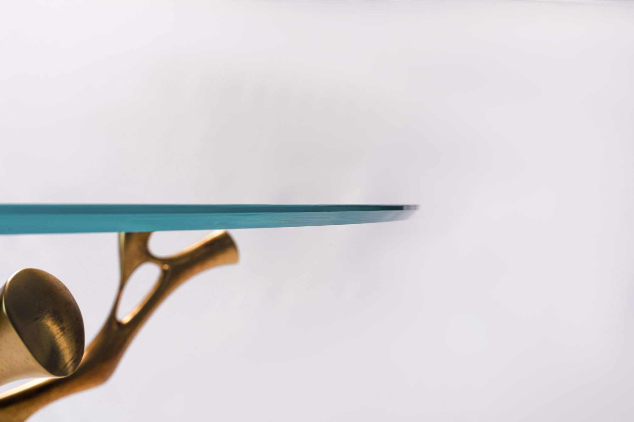 Detail of the glass edge resting on the bronze branch of the round table