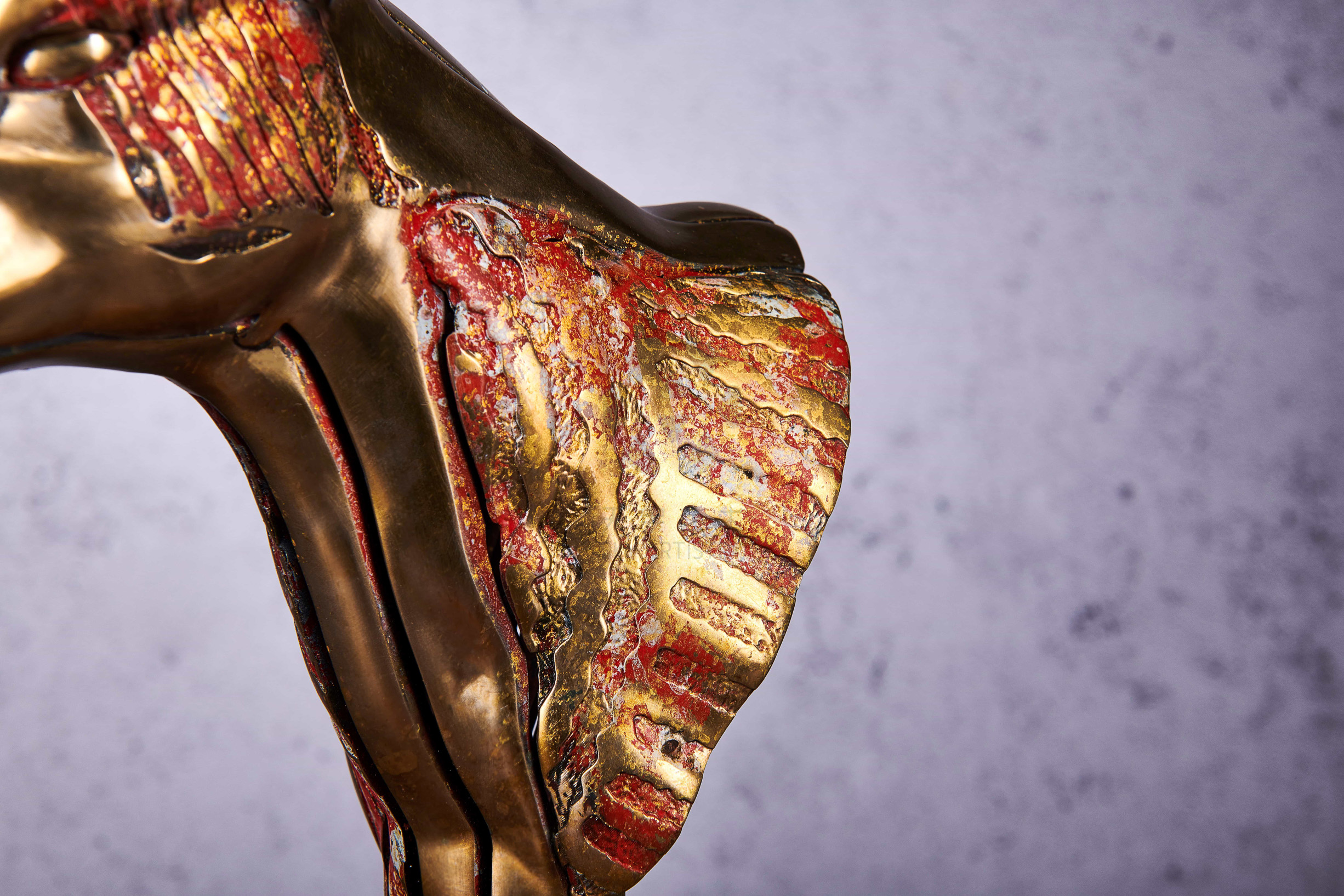 Deconstructed antelope bust in gold and coral — neck detail.