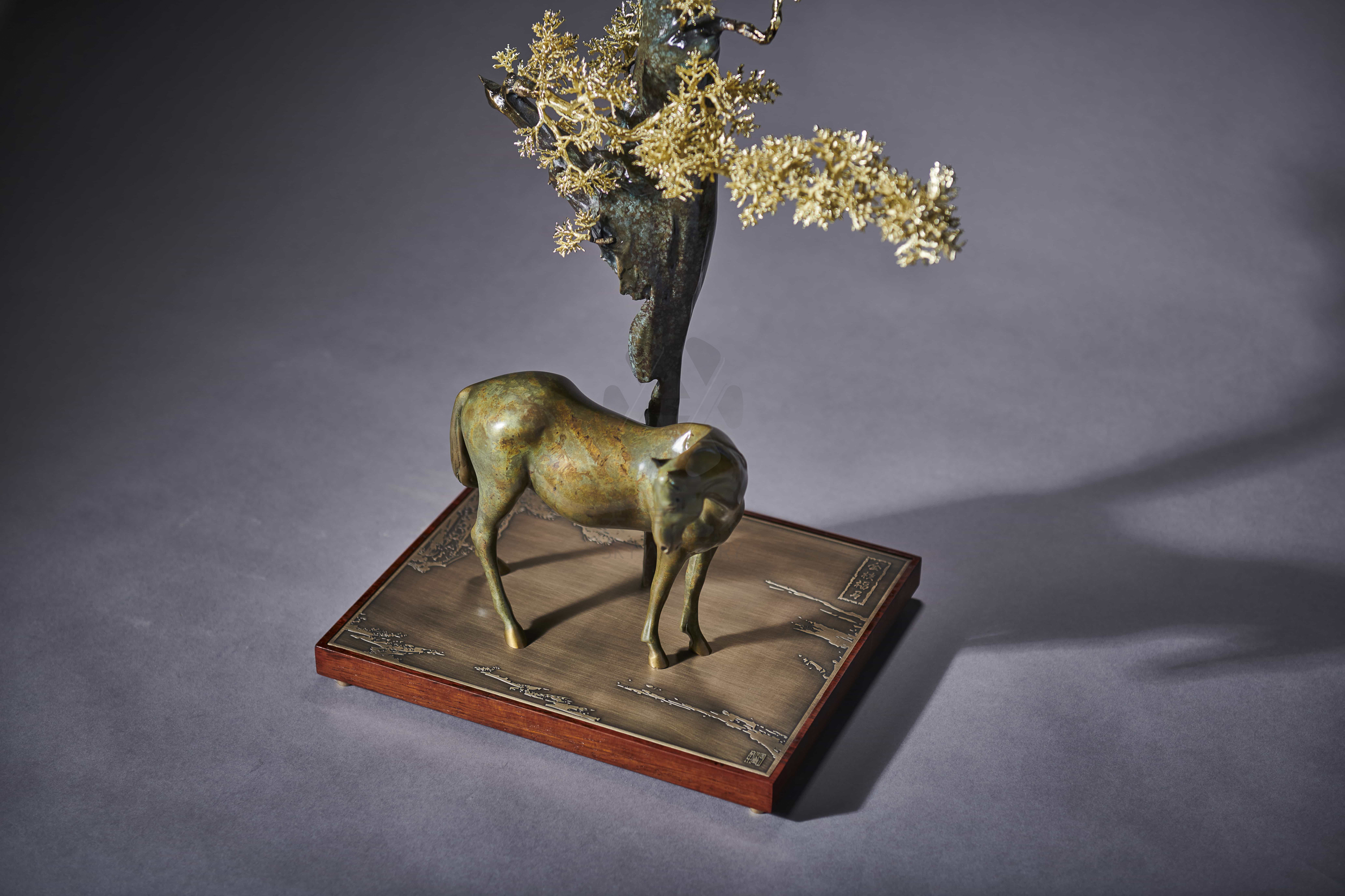 Grazing horse beneath golden-leaf tree — alt angle.