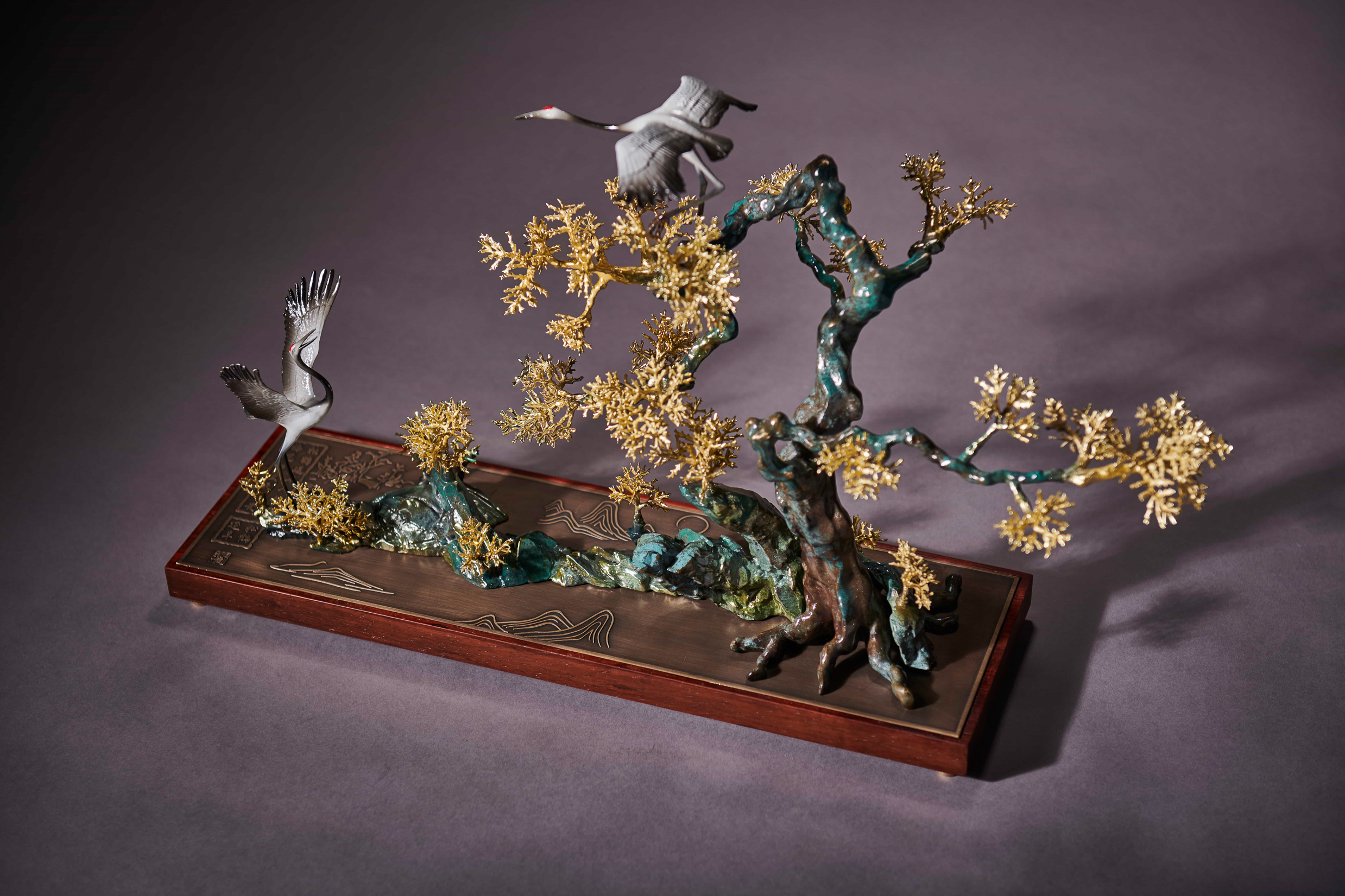 Cranes in golden pine tree tableau — alt angle.