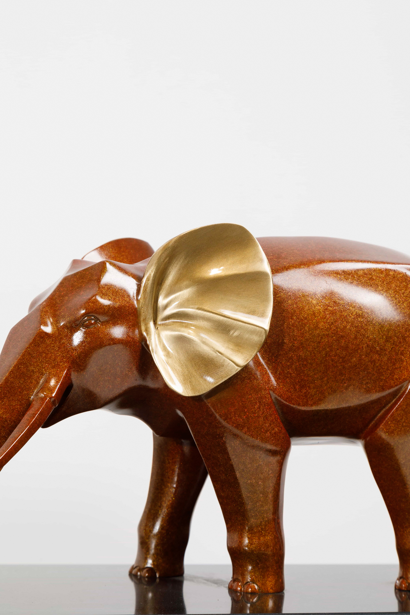 Mahogany-brown elephant family with gold ears — ear detail close-up.