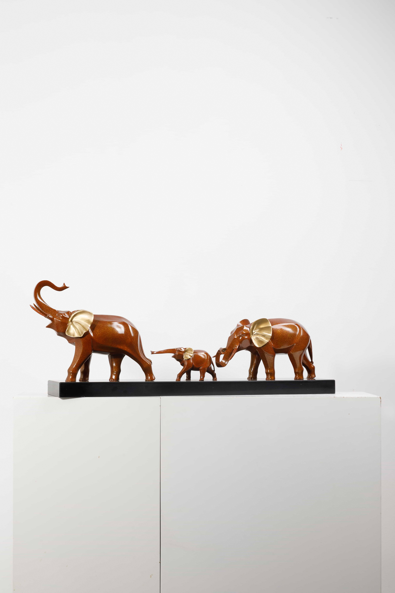 Mahogany-brown elephant family with gold ears — group front view.