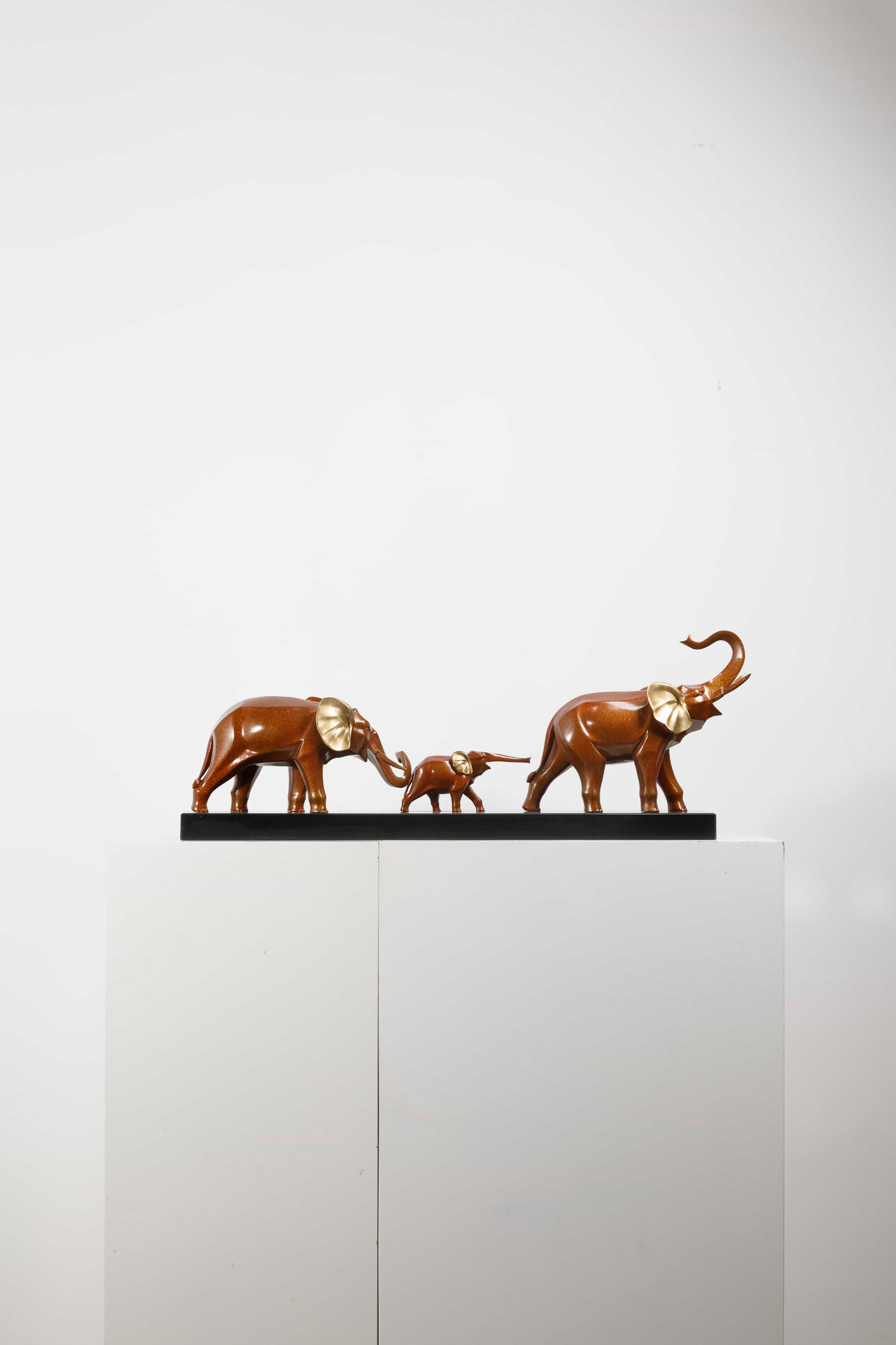 Mahogany-brown elephant family with gold ears — group wide view.