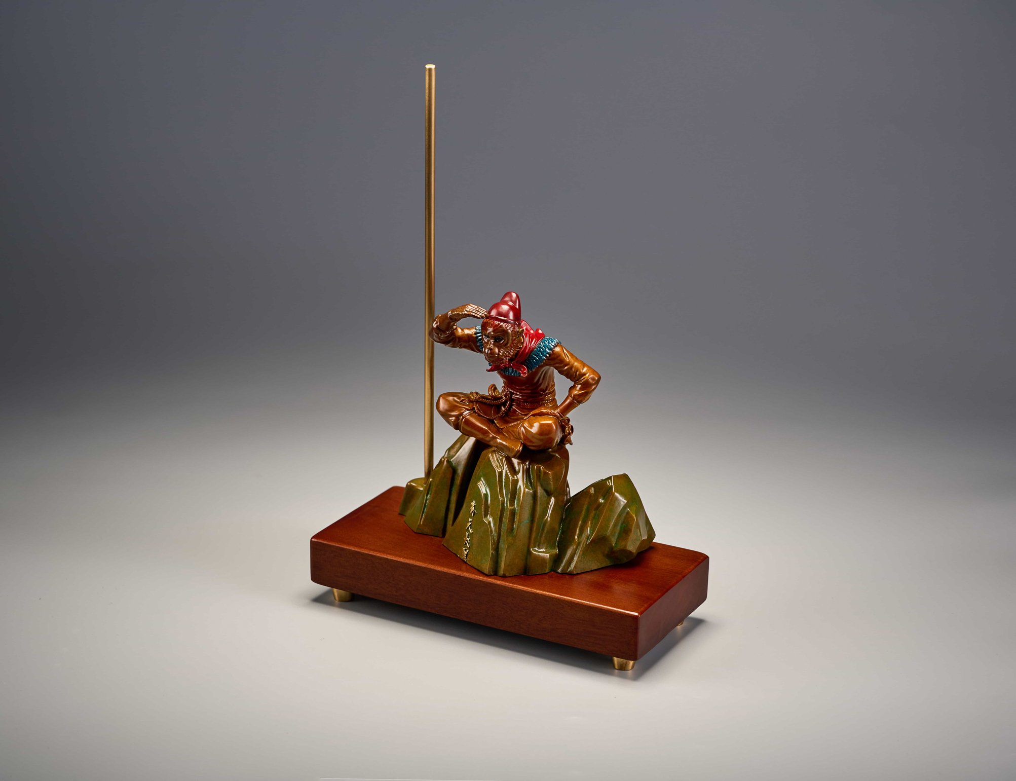 Enamel monkey king seated with golden staff — front view.