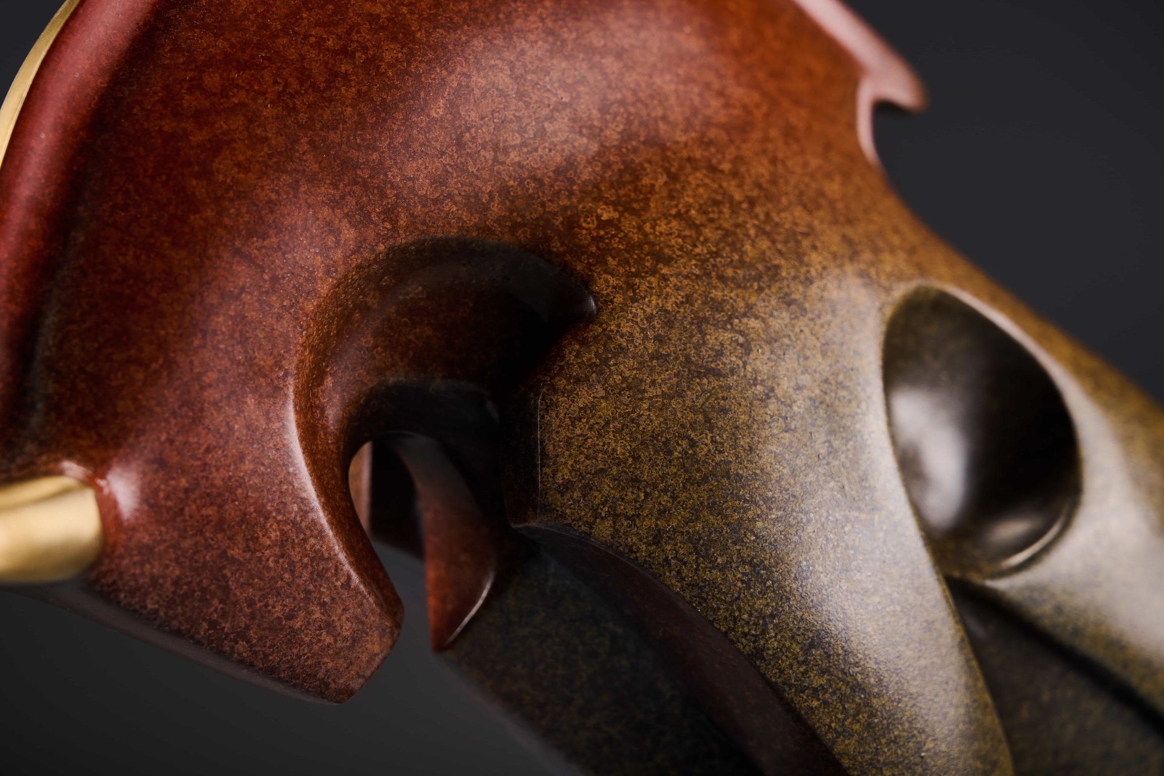 Abstract charging bull with red crest — head and horn close-up.