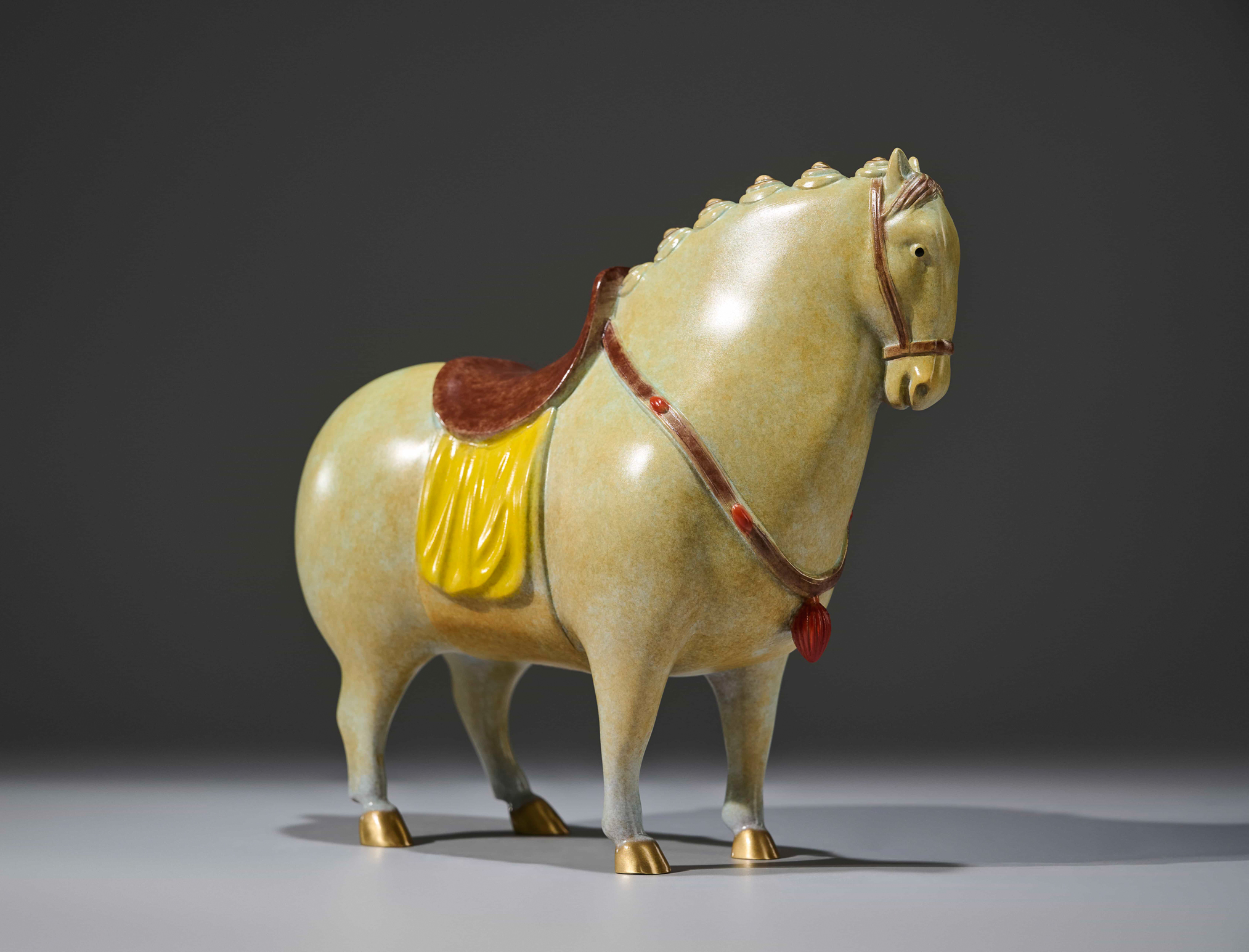Celadon-glazed tang-style horse with red saddle — front view.