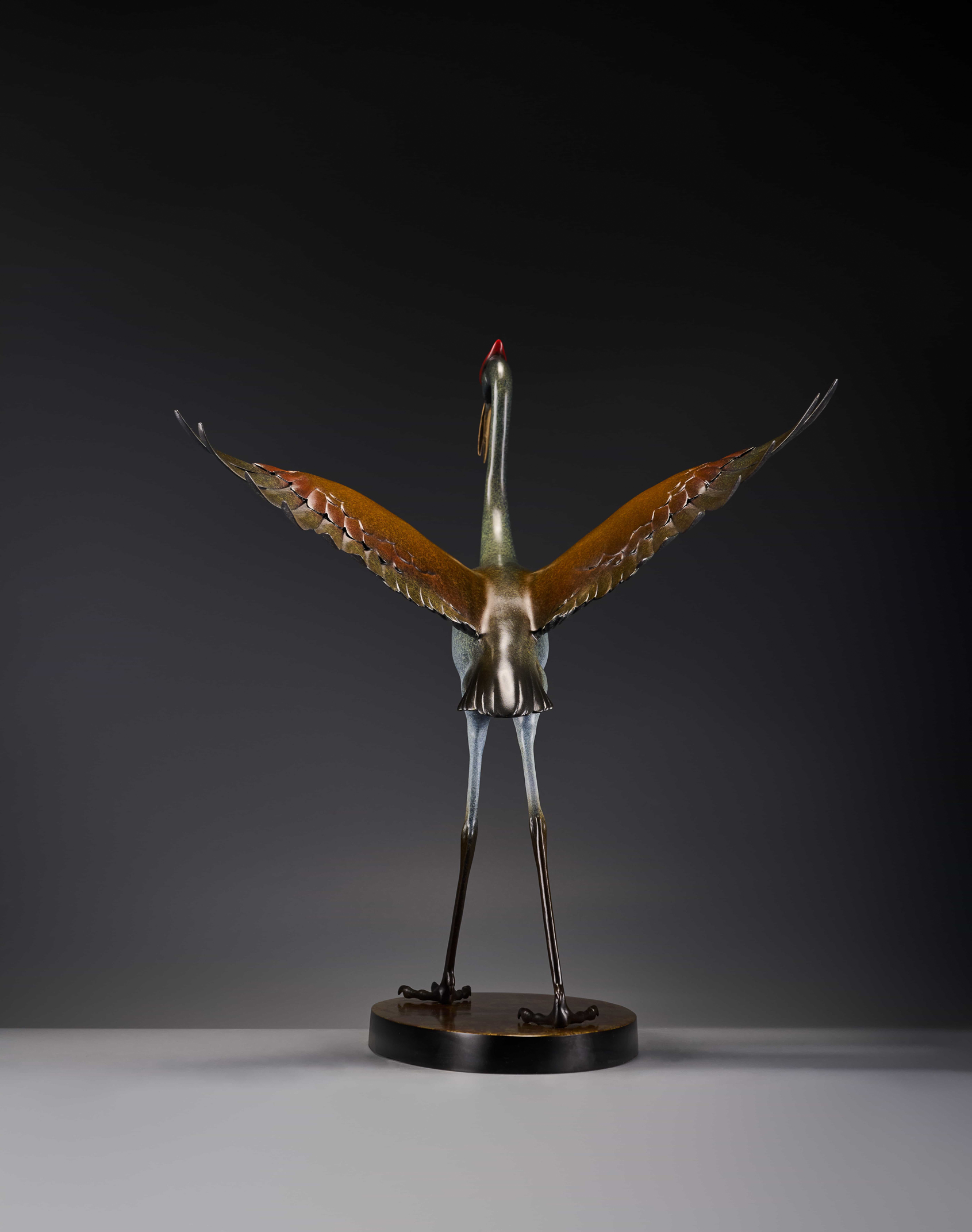 Silver crane with spread wings and red crown — rear view wings spread.