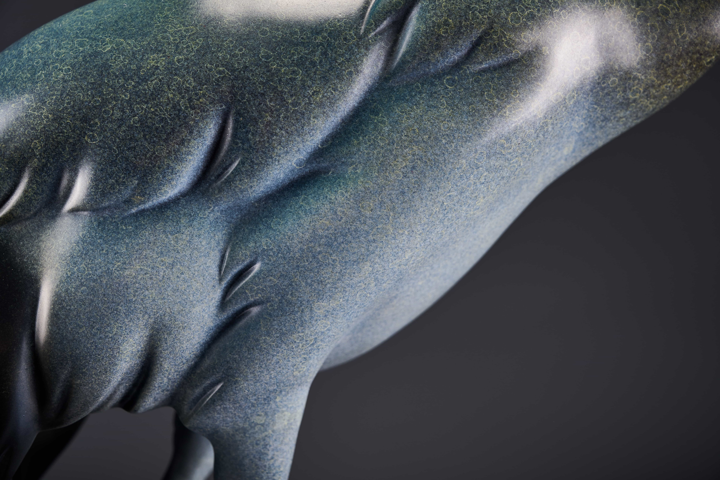 Silver-blue crane with red crown on black base — feather texture detail.