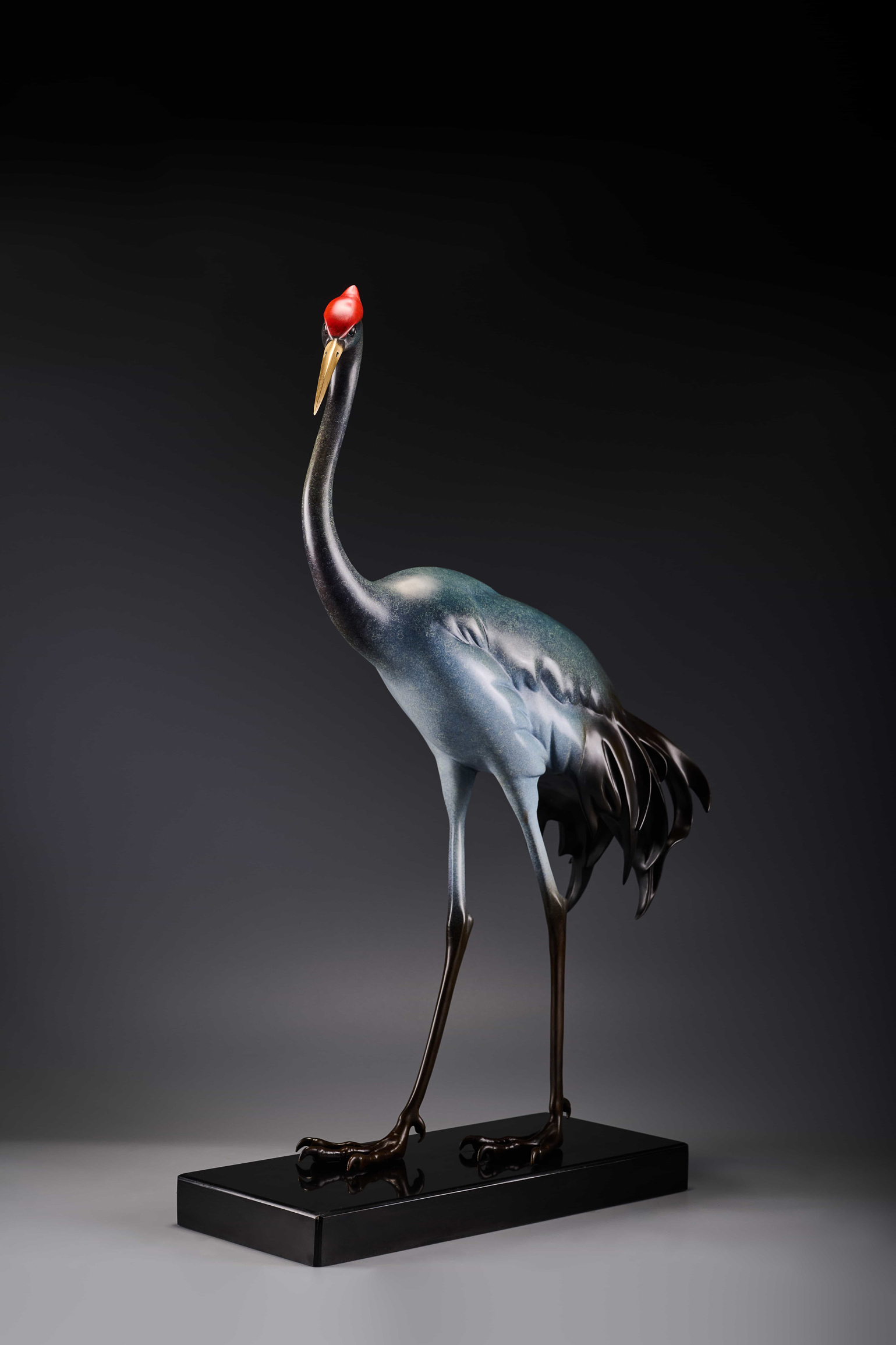 Silver-blue crane with red crown on black base — rear three-quarter.