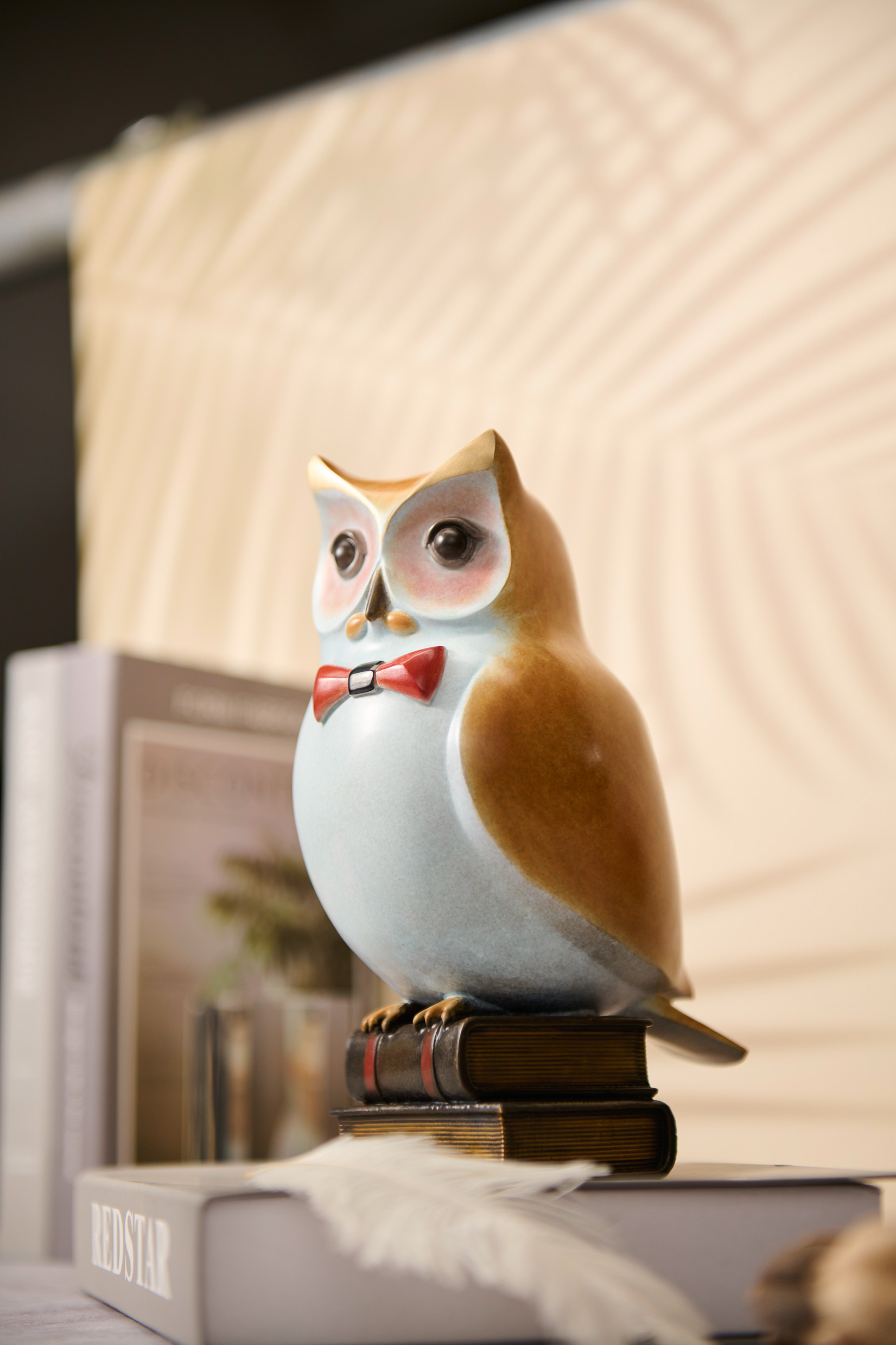 Cartoon owl with red bow tie on books — interior styled view.