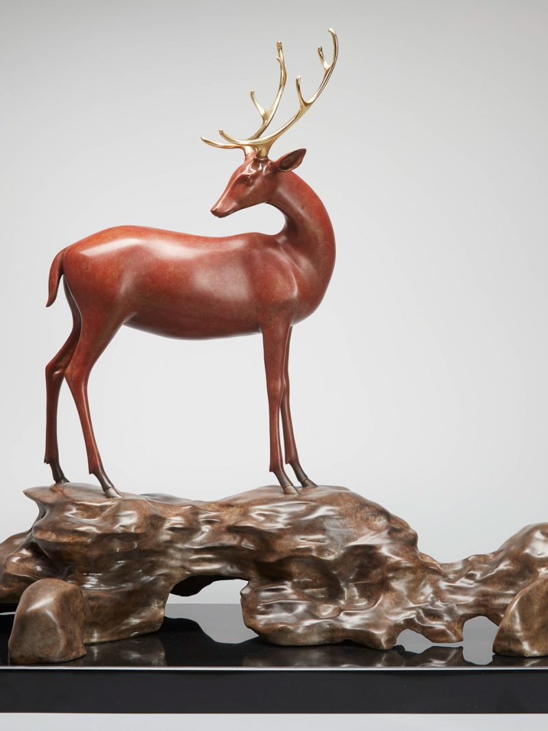 The golden-horned deer is standing on the rock.