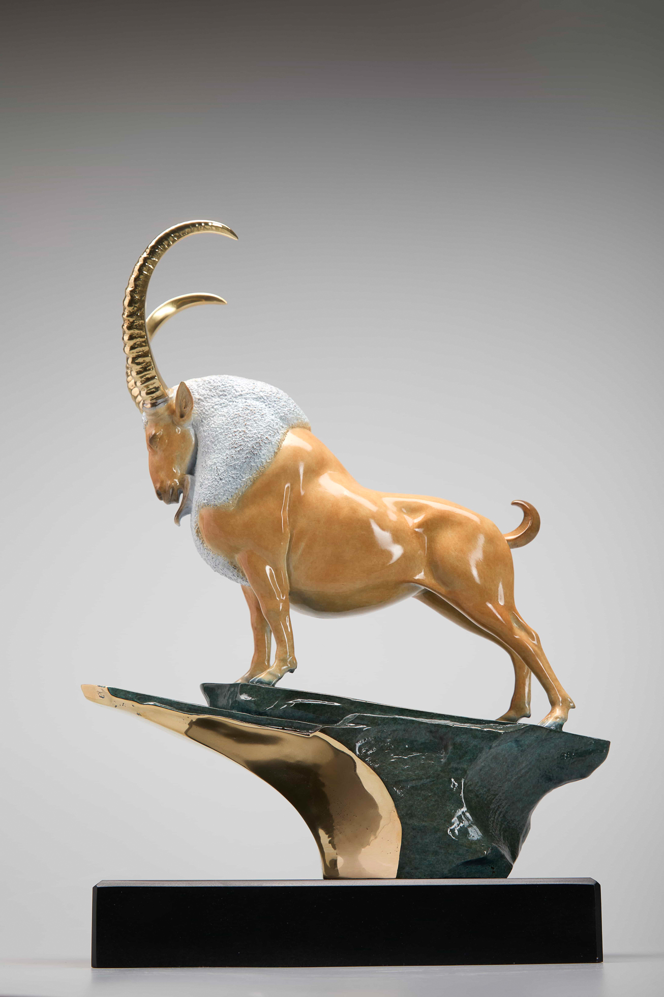 Golden ibex on green-and-gold cliff base — side view.