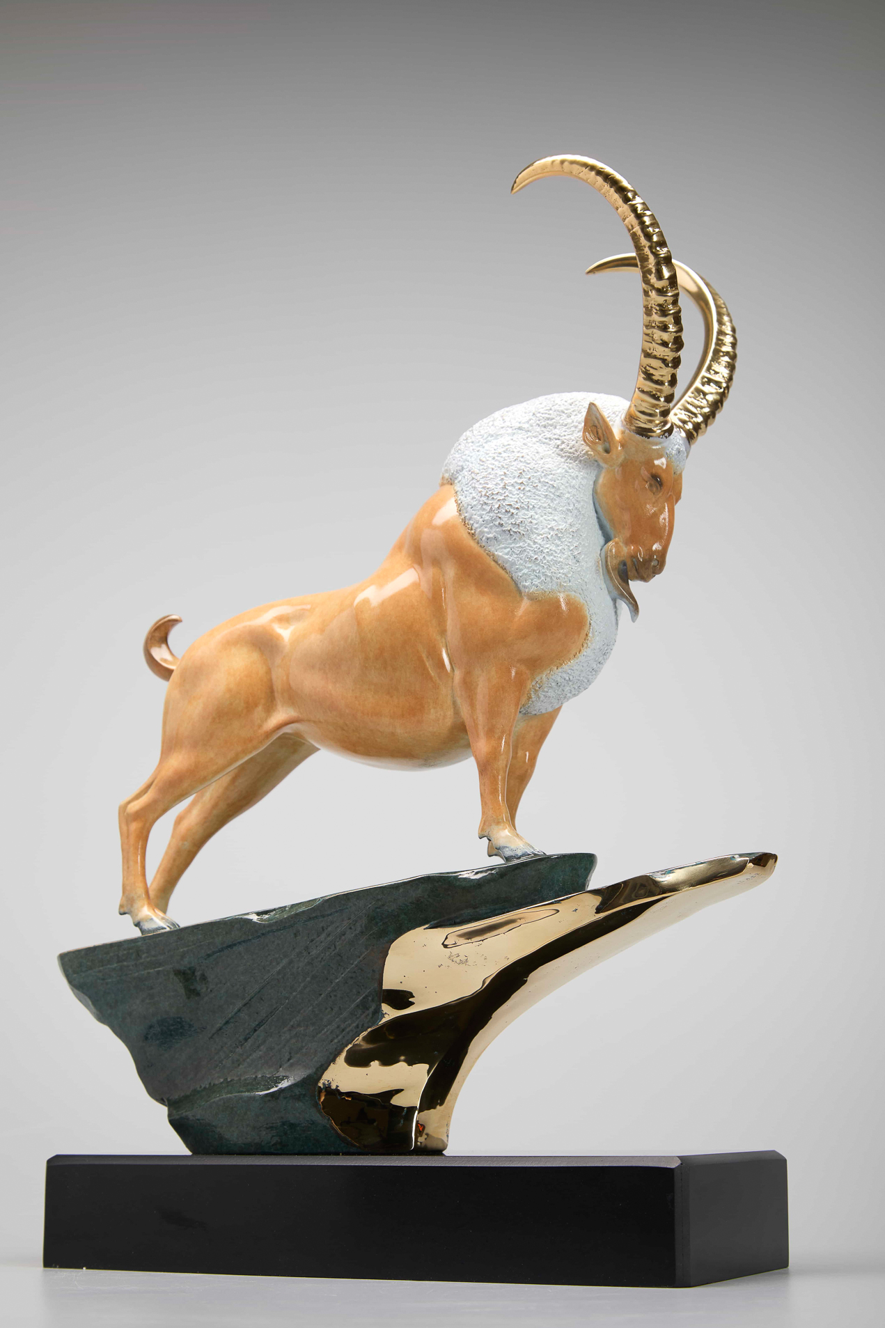 Golden ibex on green-and-gold cliff base — front three-quarter.