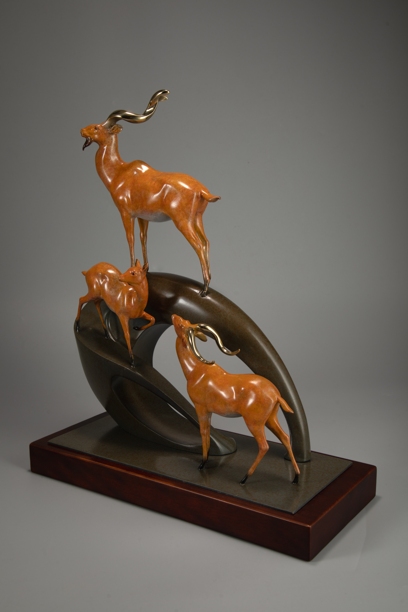Golden antelope herd ascending arc base — wooden base alt angle.