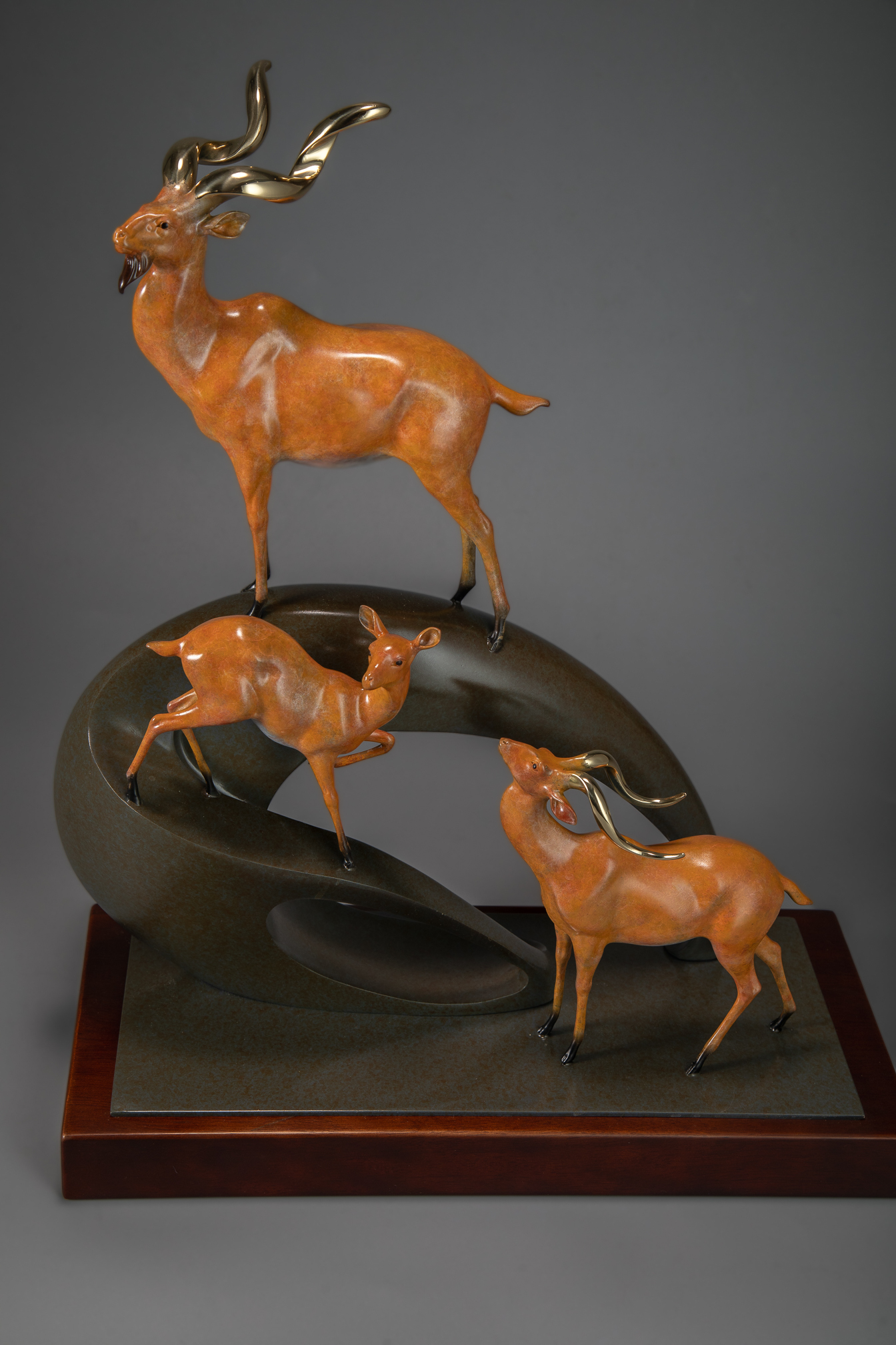 Golden antelope herd ascending arc base — wooden base alt angle.