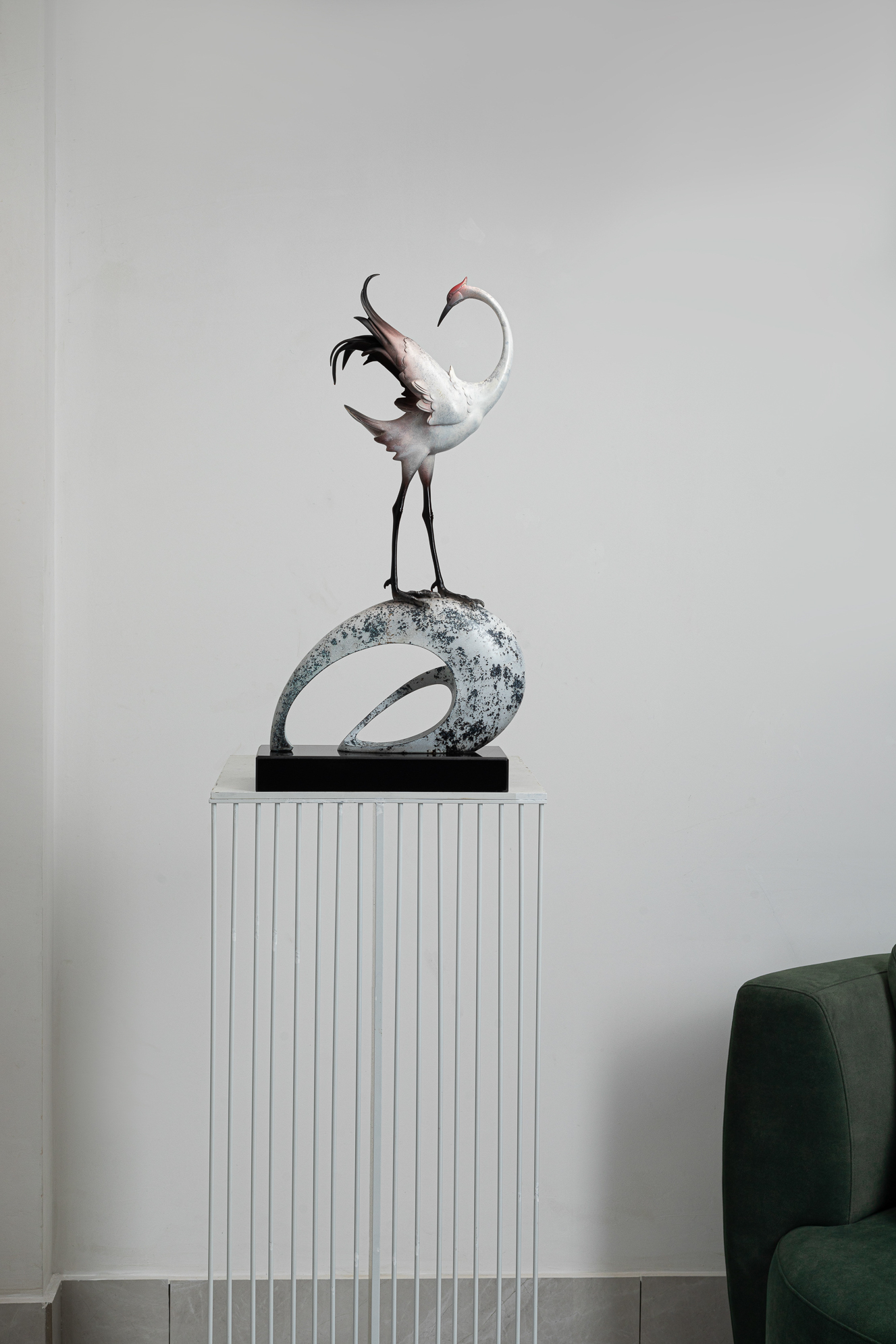 White crane preening on abstract ring base — styled interior view.