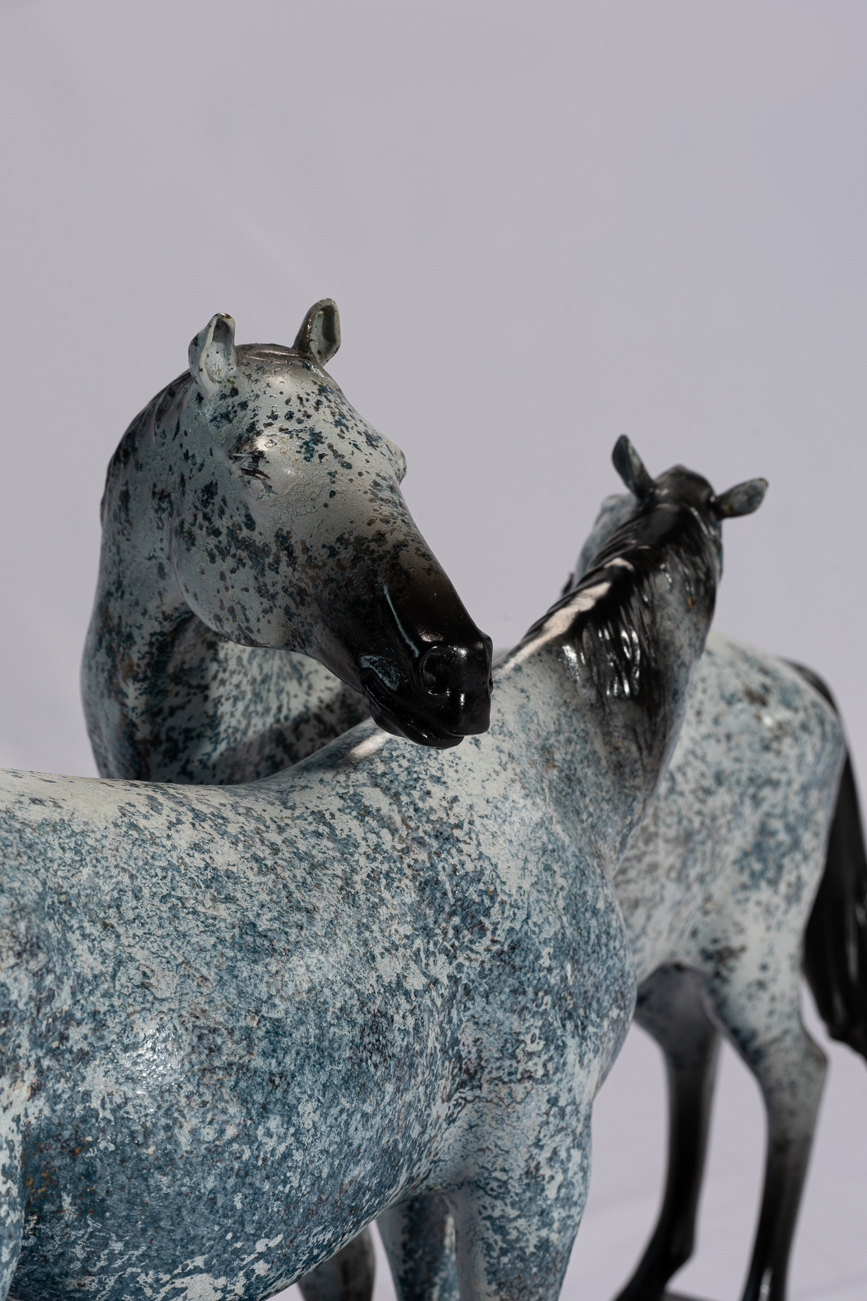 Grey patina pair of horses — heads close-up.
