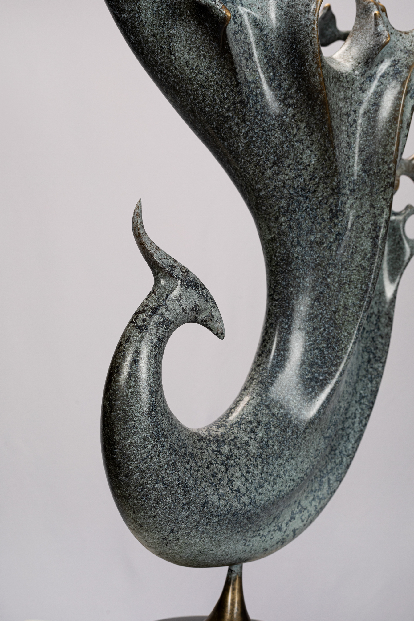 Abstract phoenix with flowing tail on black base — flowing body close-up.