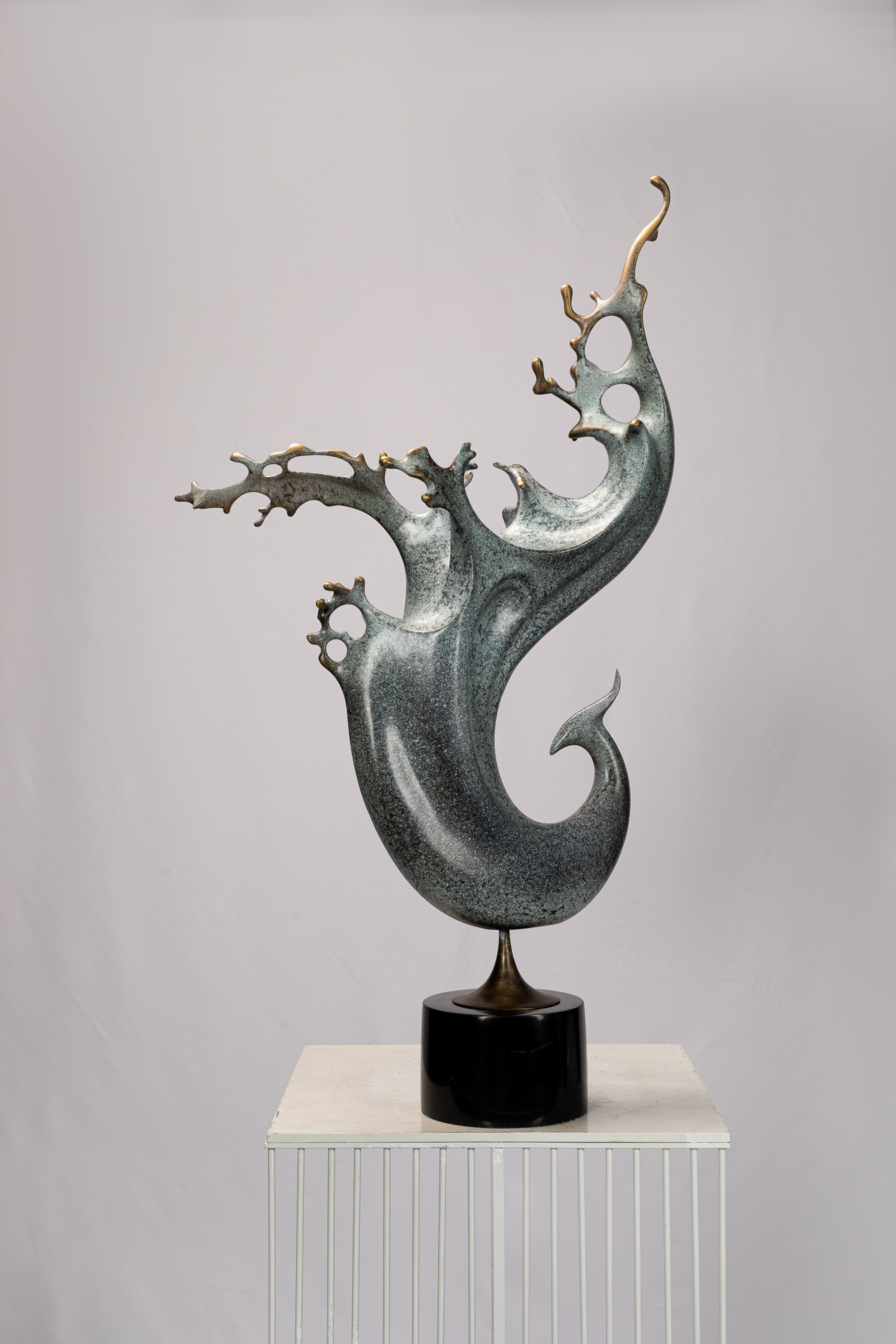 Abstract phoenix with flowing tail on black base — three-quarter view.