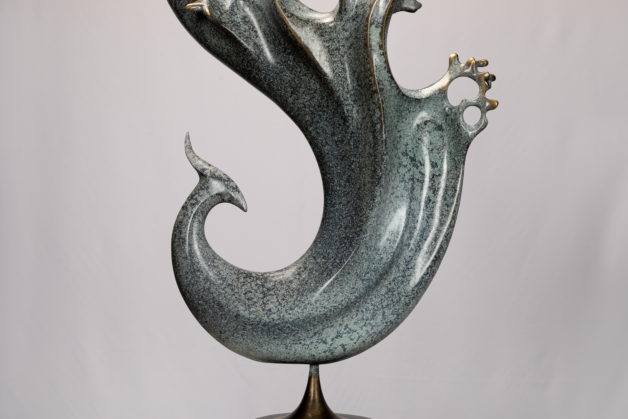 Abstract phoenix with flowing tail on black base — tail curl close-up.