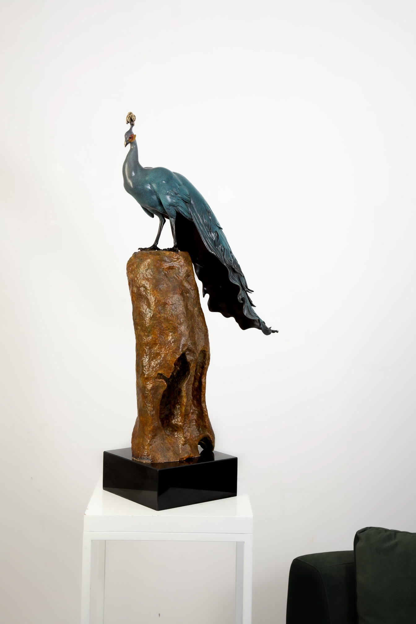 Patina-green peacock standing on tall rock — main side view.