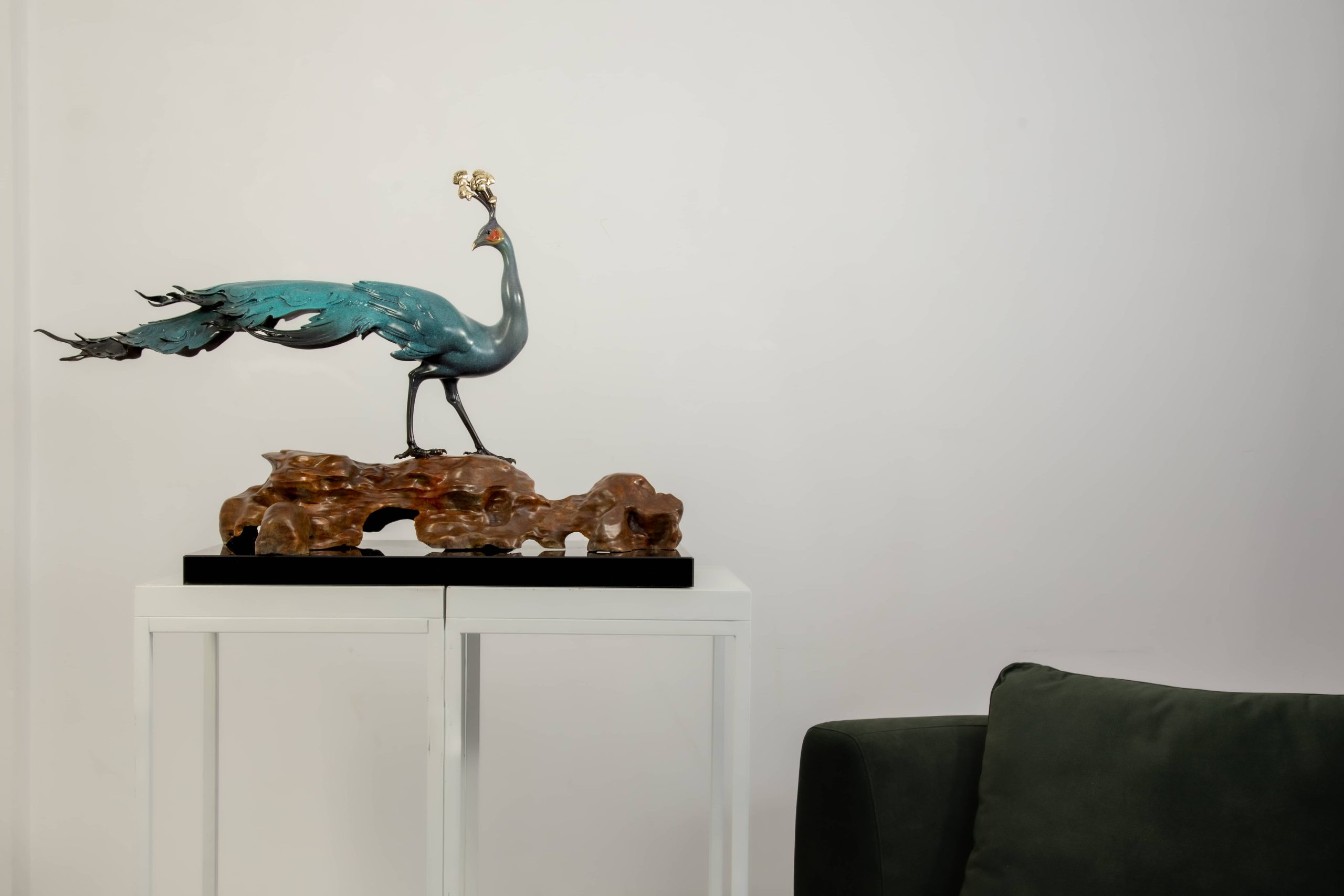 Patina-green peacock on rock base — interior styled view.