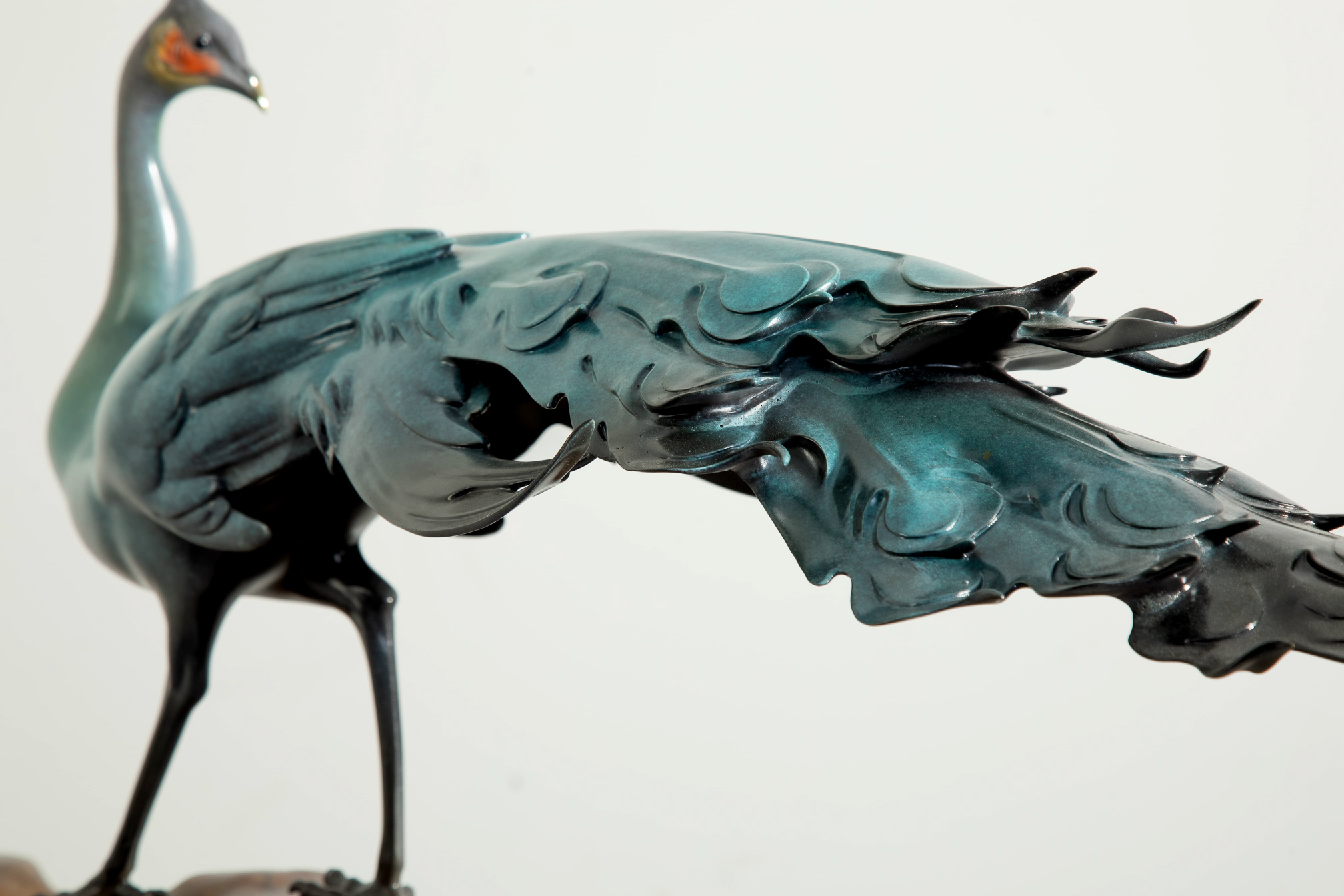 Patina-green peacock on rock base — tail plumage close-up.