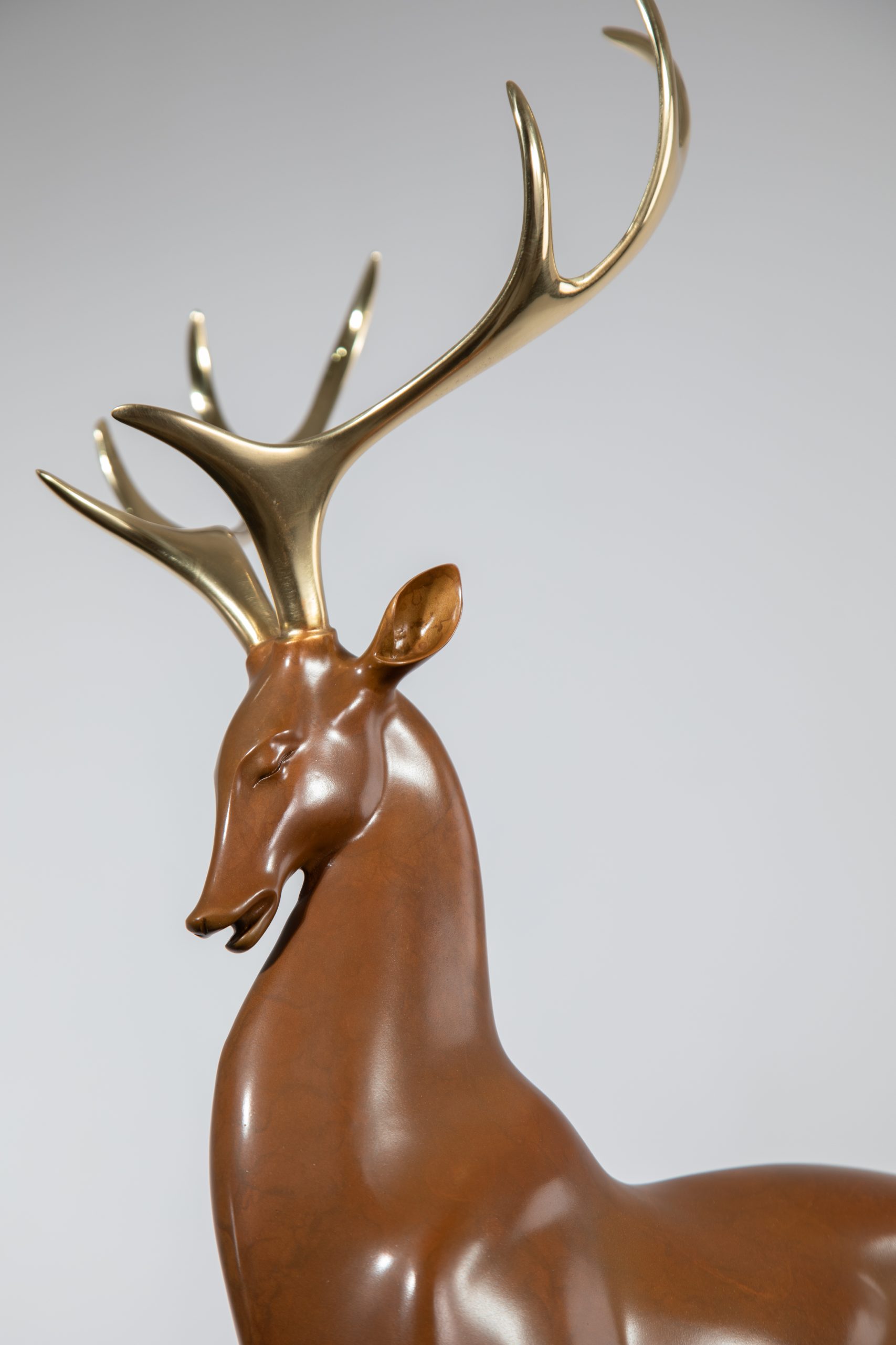 Brown deer with golden antlers on black base — head-and-antler detail.